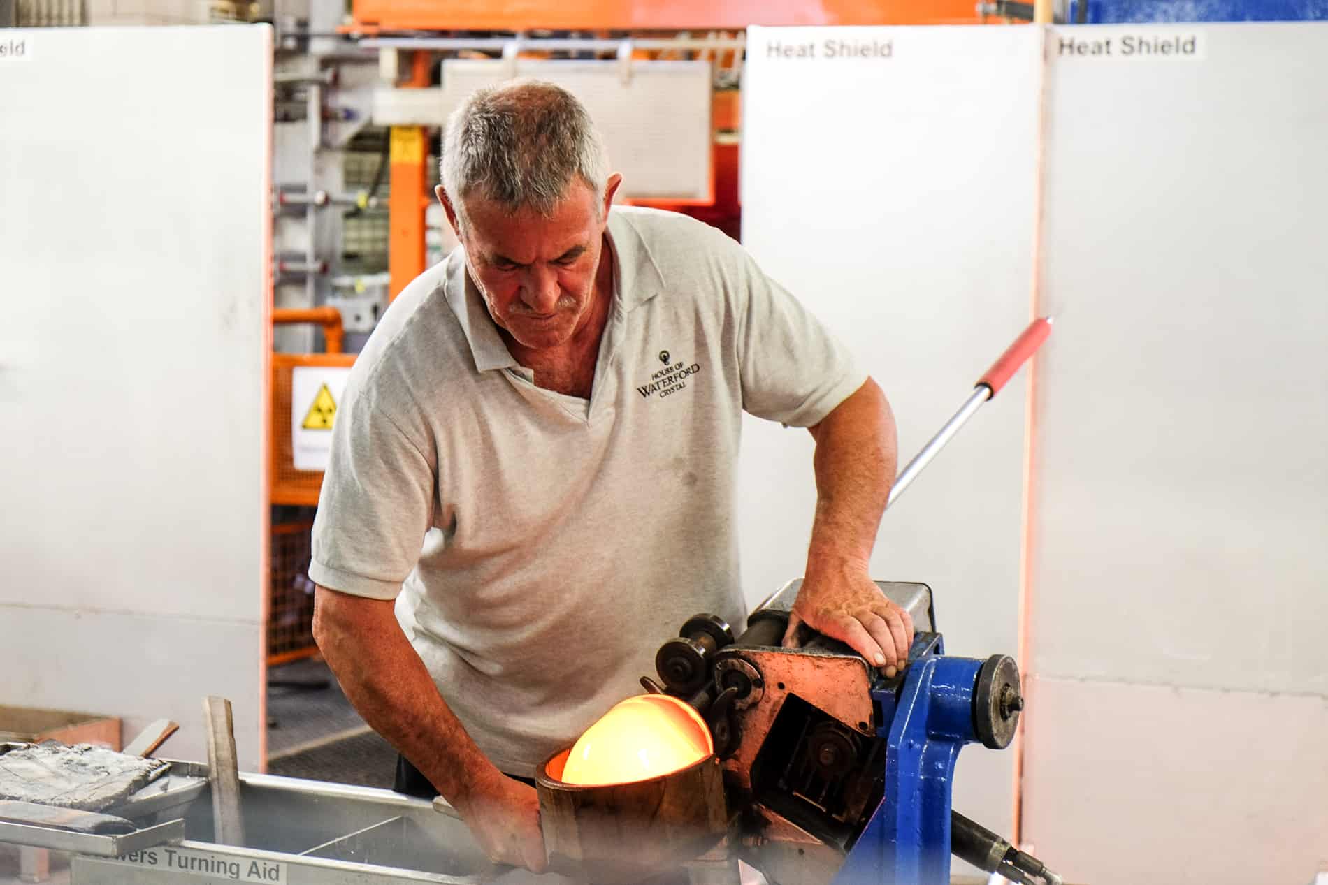 A glass worker witha. flaming yellow mould at House of Waterford Crystal Factory in Ireland.