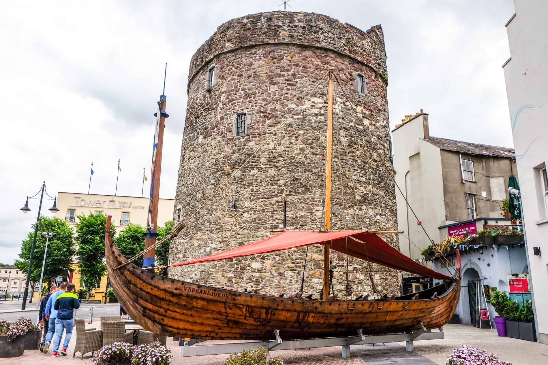 A stone tower and a replica Viking boat in Waterford, Ireland. 