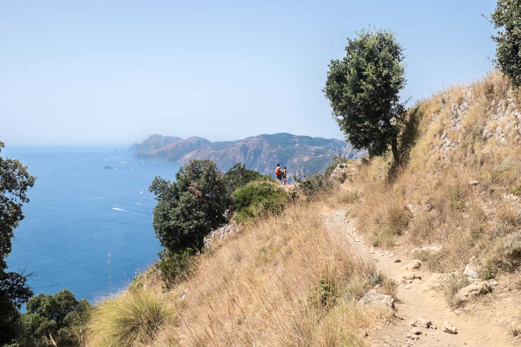 Two hikers on the cliff top Path of the Gods high above the Amalfi Coast.