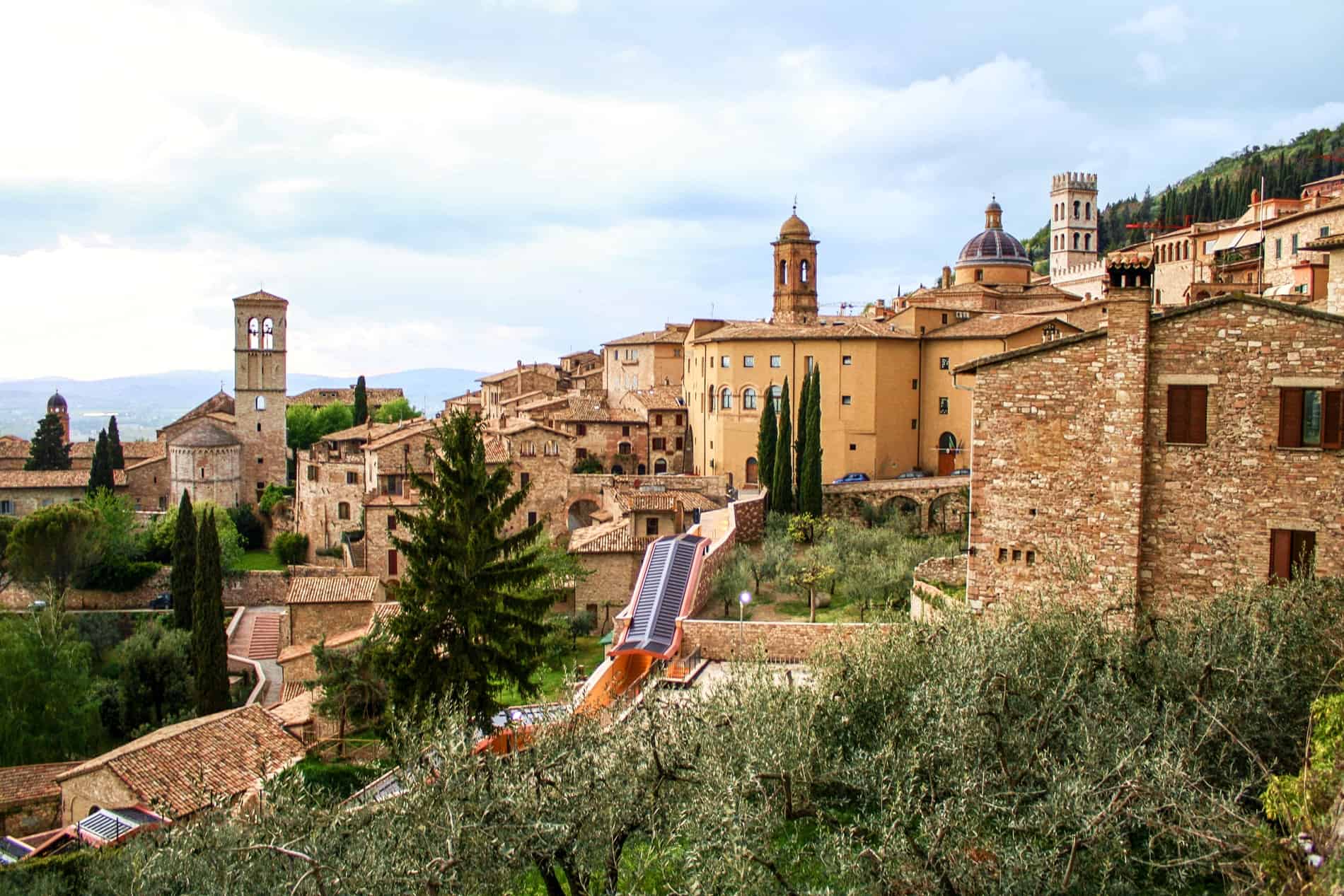 An elevated view over the golden stone hilltop town of Assisi, Italy. 