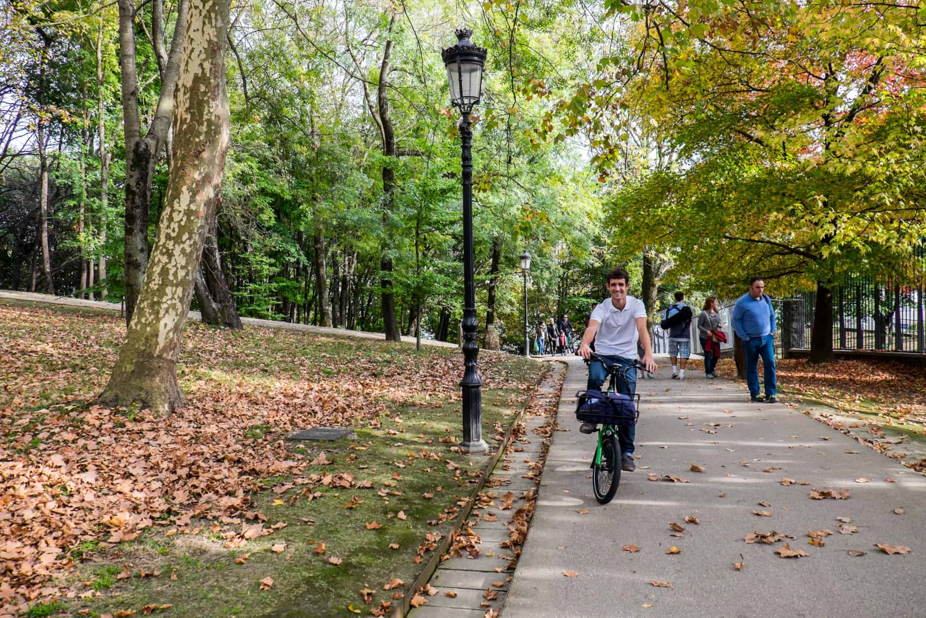 A man cycles through a green park with black lamp poles on a bike tour in San Sebastian, Spain. 