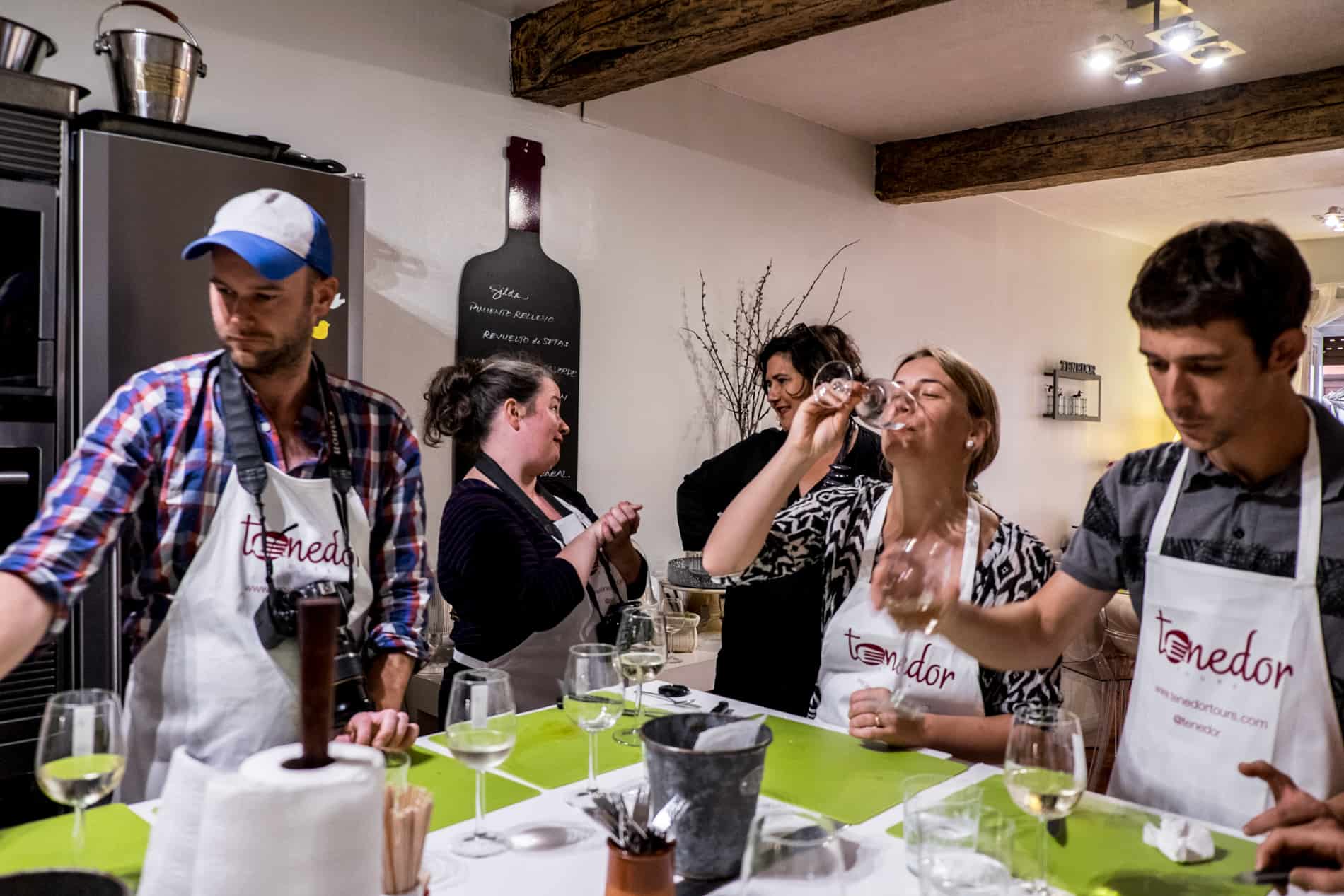 A group prepares food on green chopping boards, while drinking wine during a Pintxos cooking class. 