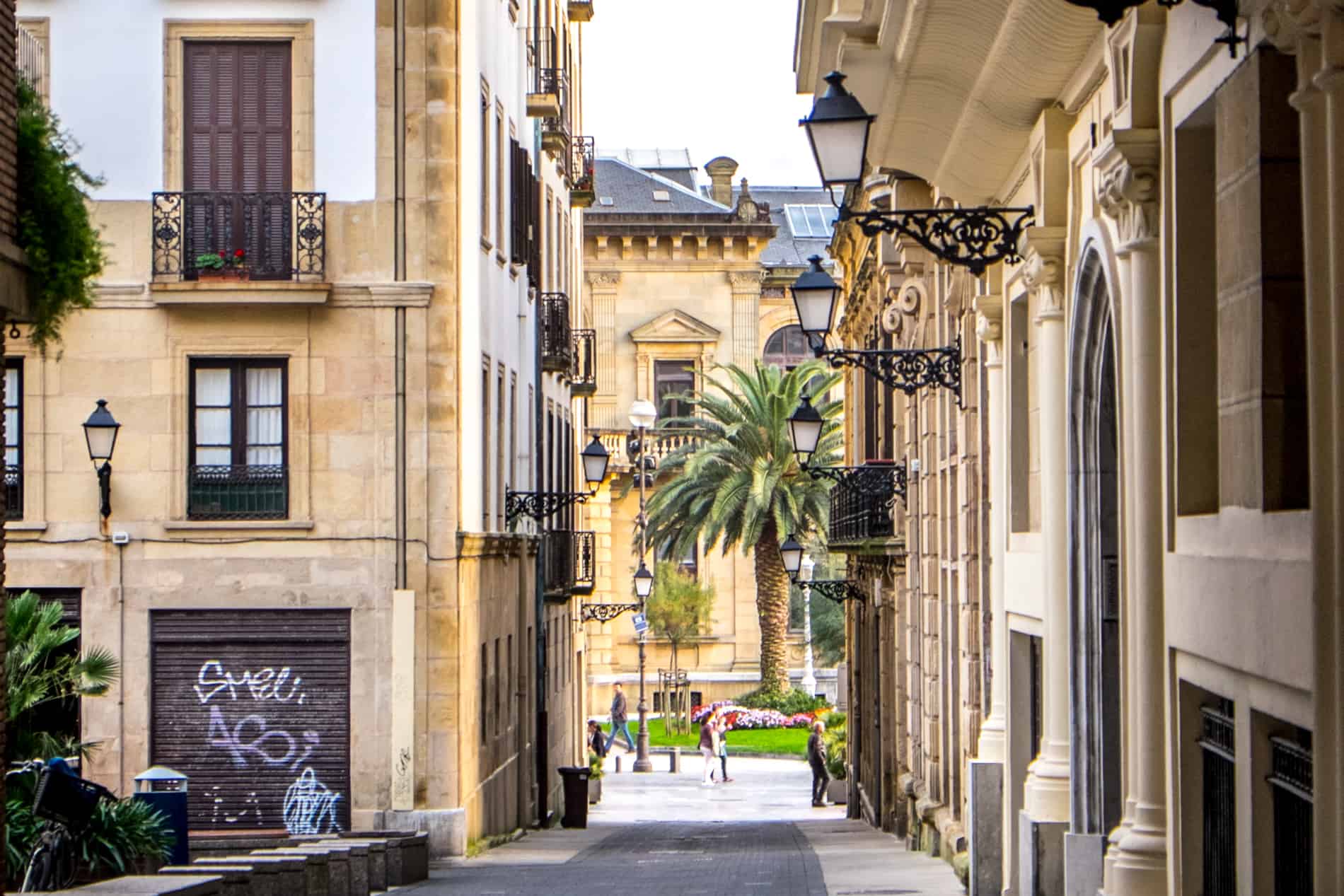 Classic buildings with golden stone facades, balconies and black street lamps in the Romantic Area of San Sebastian, Spain. 