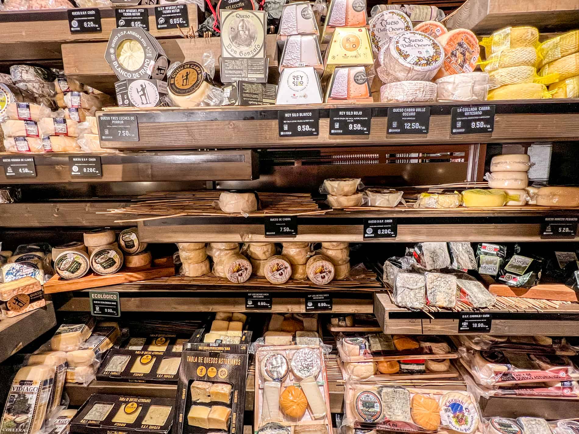 A selection of packaged cheeses on wooden shelving in Oviedo, Asturias, known as 'El Pais de Los 40 Quesos' (the land of 40 cheeses).