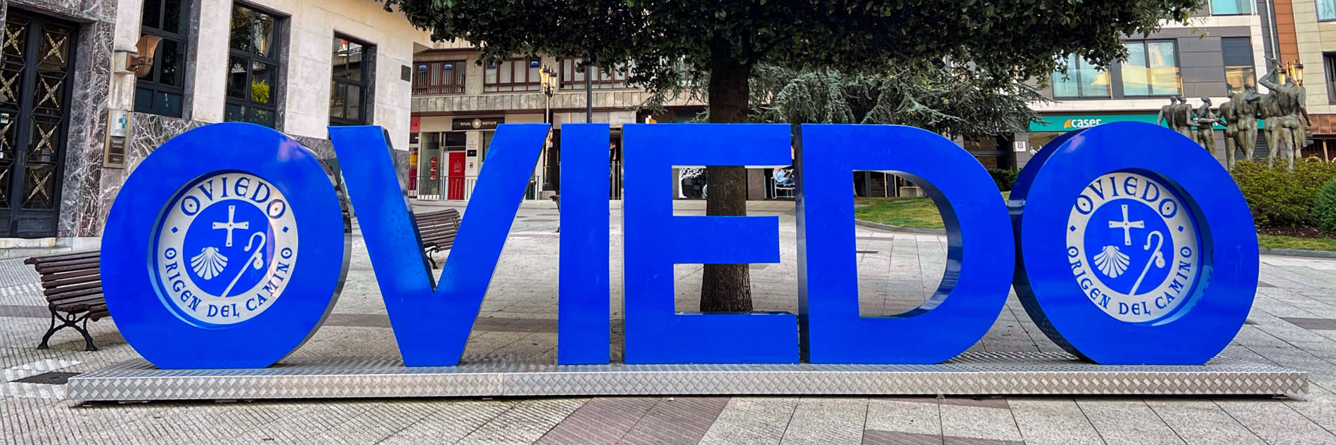 A blue letter sign for Oviedo in Spain. The wording in the 'O' letters reads "Oviedo. Origen Del Camino" - the origin city of the Camino de Santiago. 