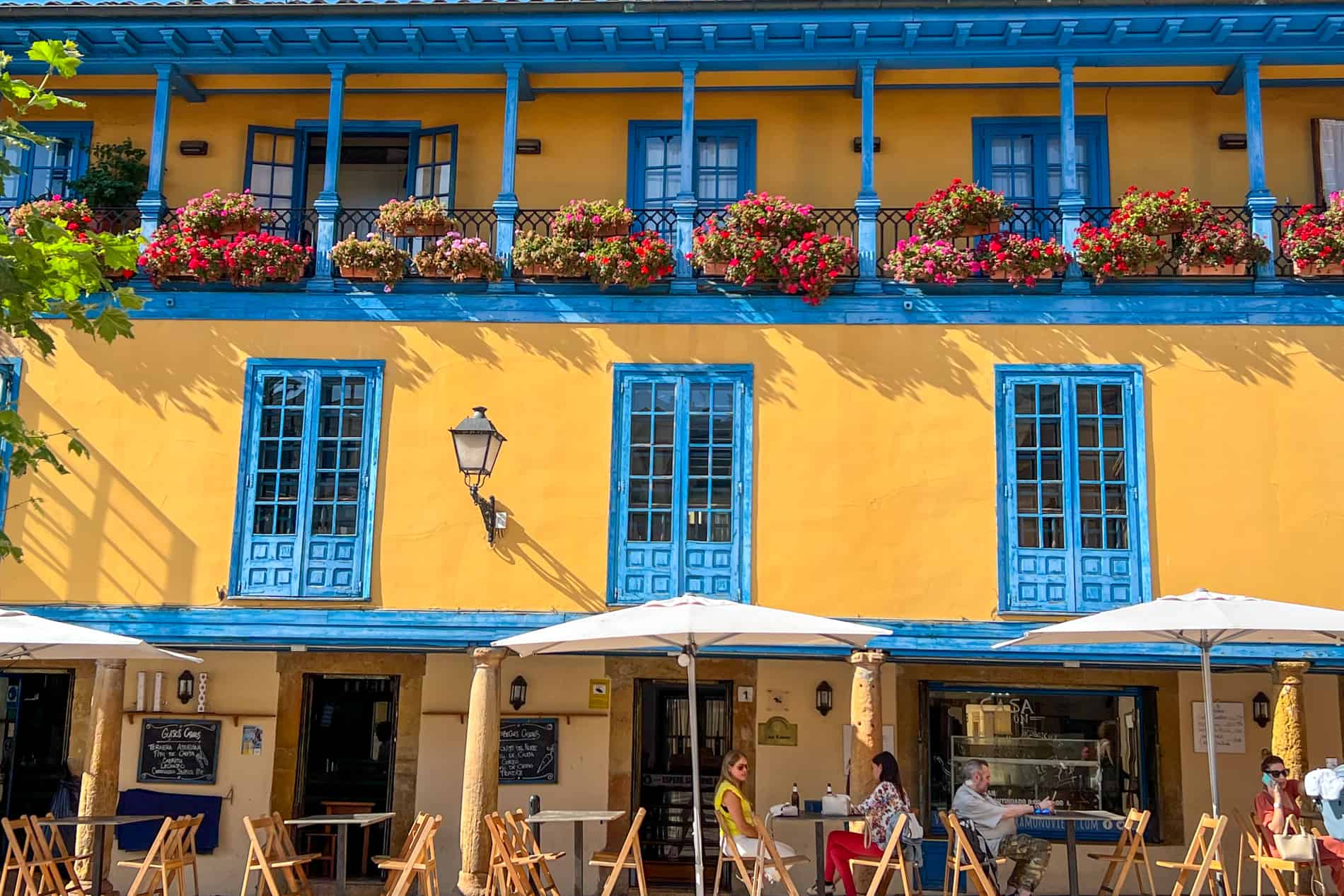 A yellow building with blue windows and balcony columns, found in Plaza Daoiz y Velarde in Oviedo, Spain. 
