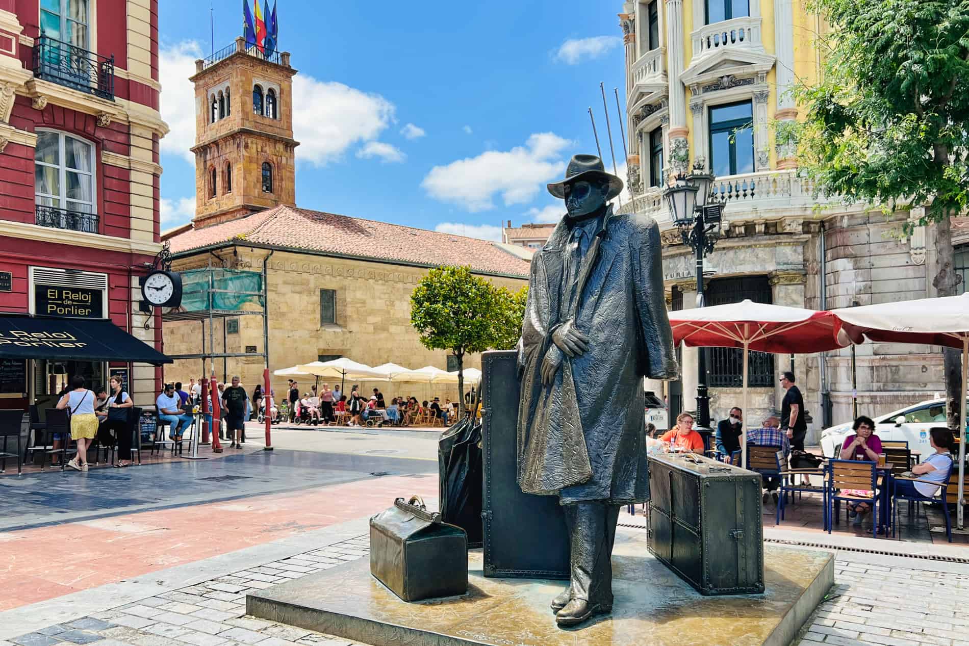 The El Regreso de Williams B. Arrensberg' traveller statue in Oviedo of a man in a long coat leaning against his suitcases.