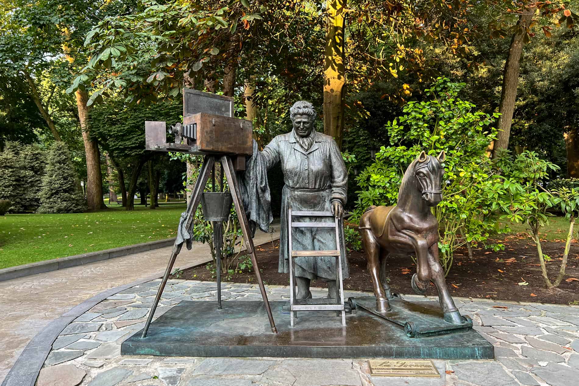 The La Torera statue in oviedo's San Francisco Park of a photographer, with a camera on a tripod, rocking horse and a chair. 