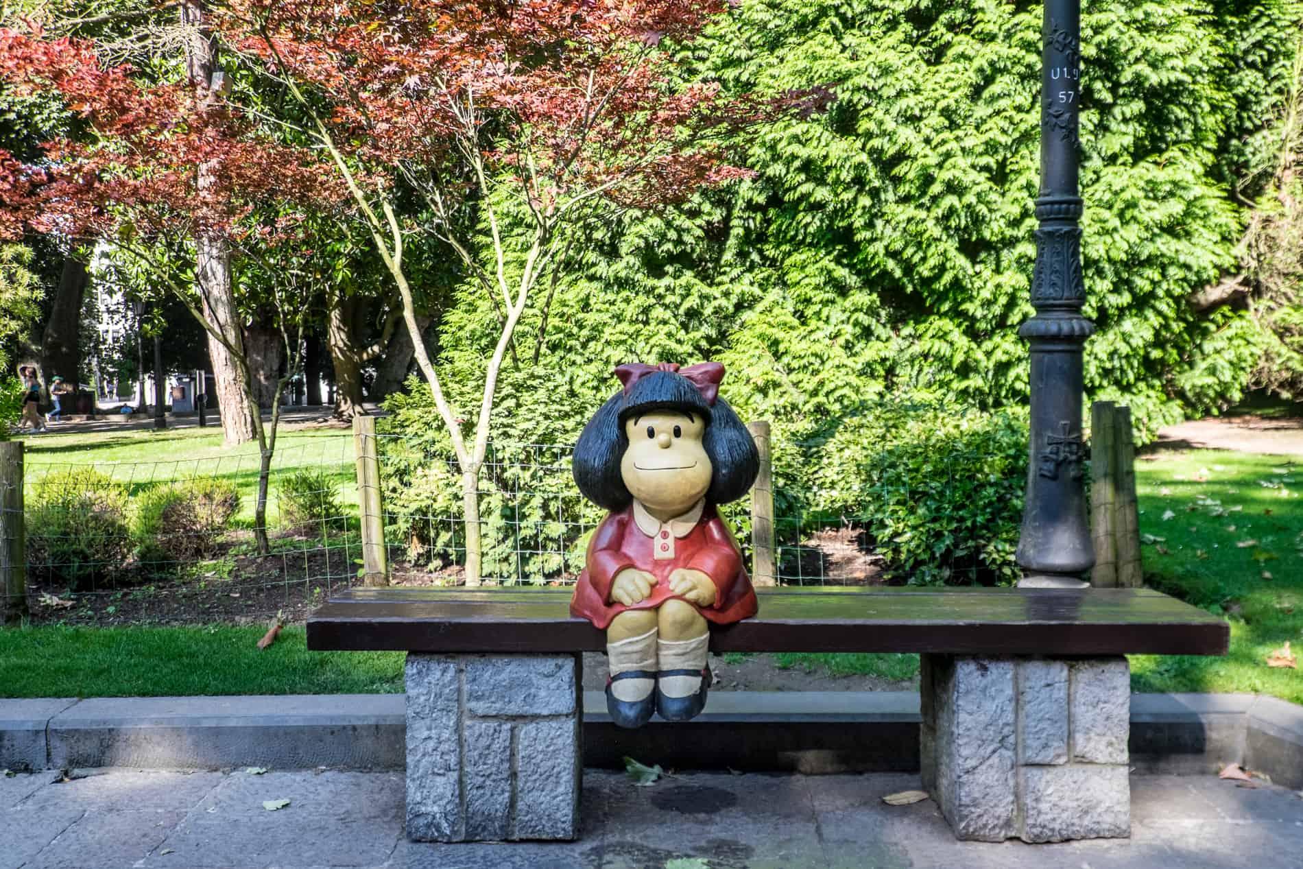 The 'Mafalda' sculpture in Oviedo is an Argentine satirical cartoon character with black hair and a red dress. She sits on a bench in San Francisco Park.