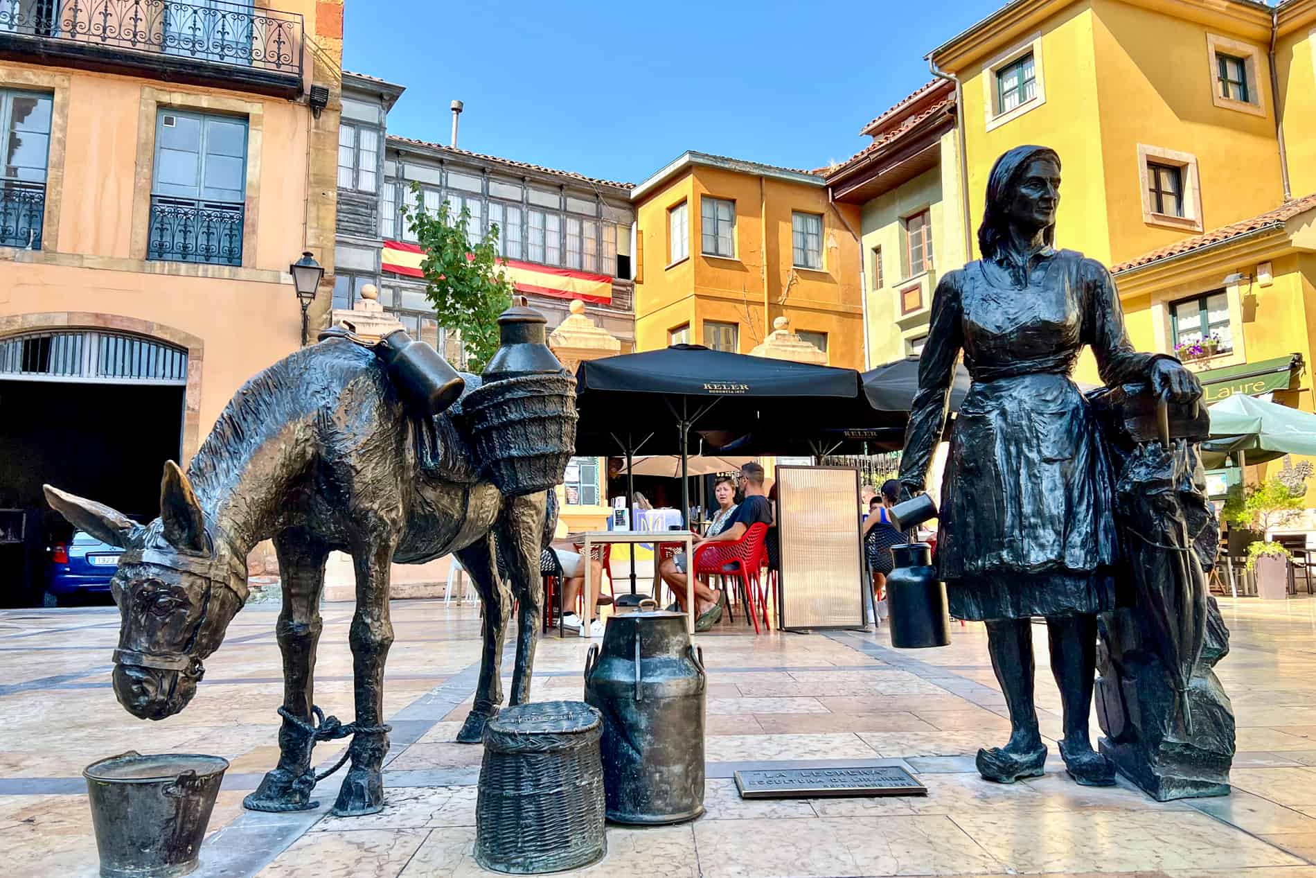 The 'La Lechera' statue in Oviedo of a milkmaid with her donkey in a colourful cafe-lined square. 