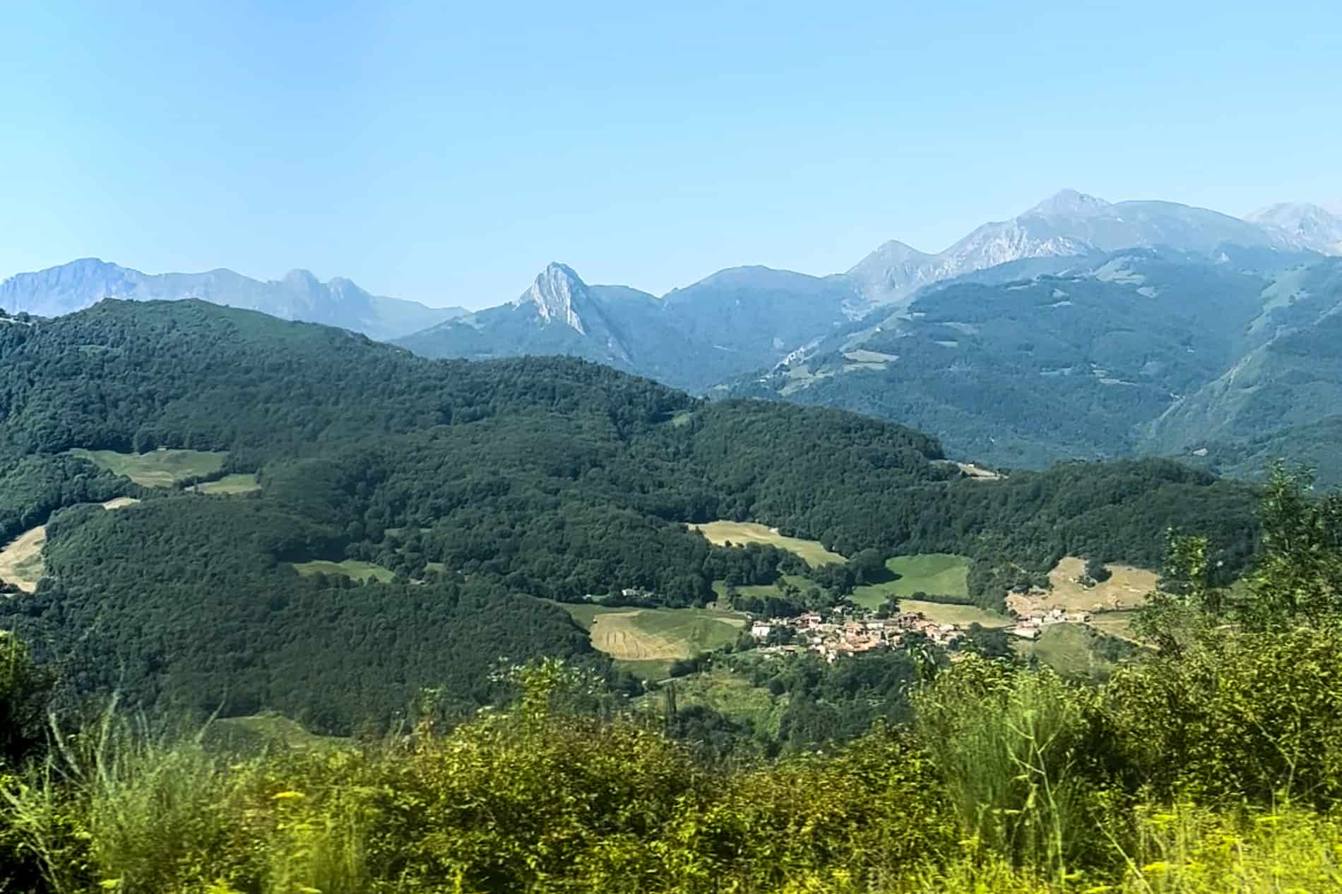 Rolling green valleys in front of the mountain ridges of Picos de Europa National Park in Asturias, Spain.