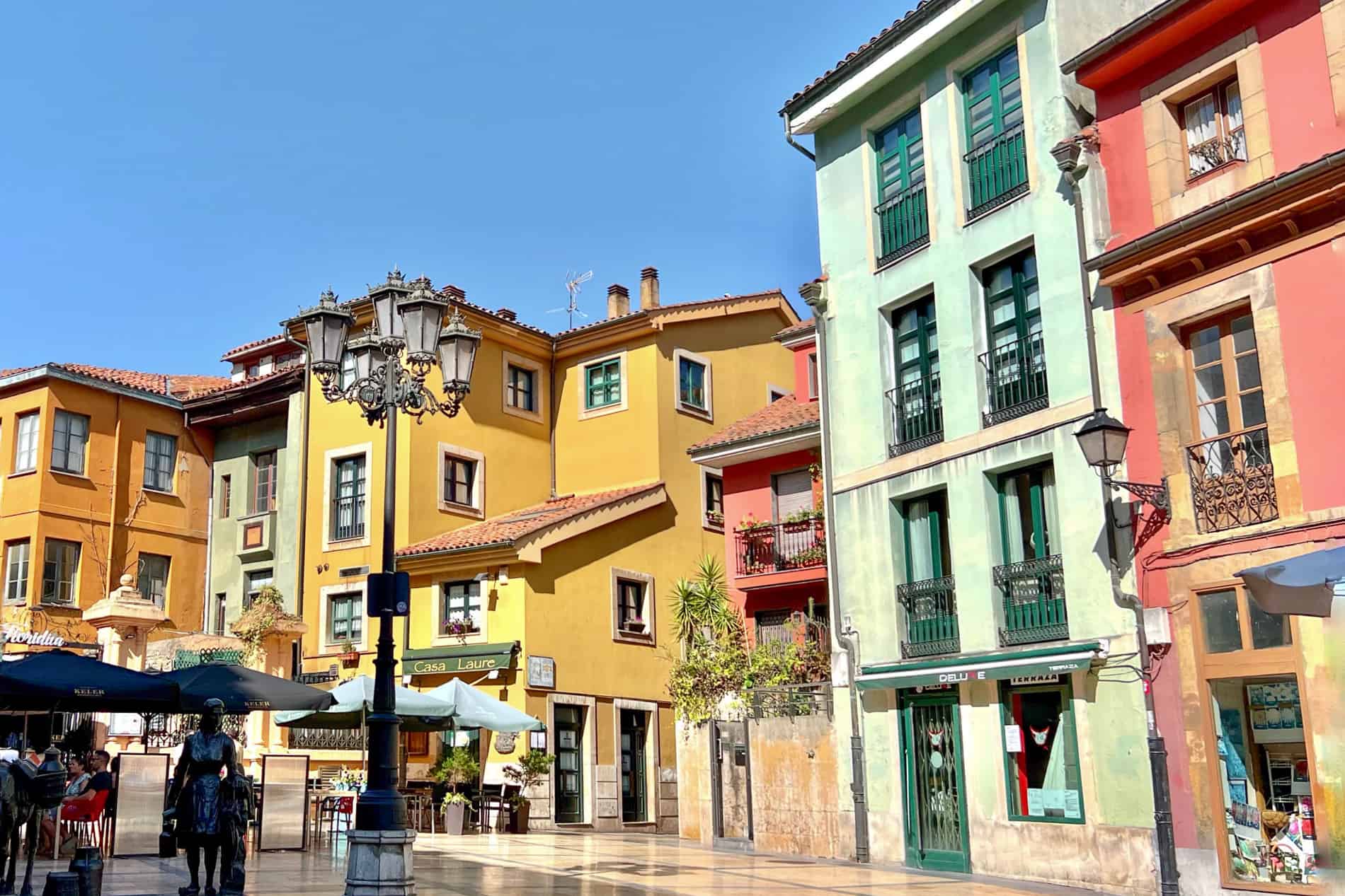 Orange, yellow, pink and mint green buildings with shops and cafes, fill the cosy Plaza Trascorrales square in Oviedo, Spain. 