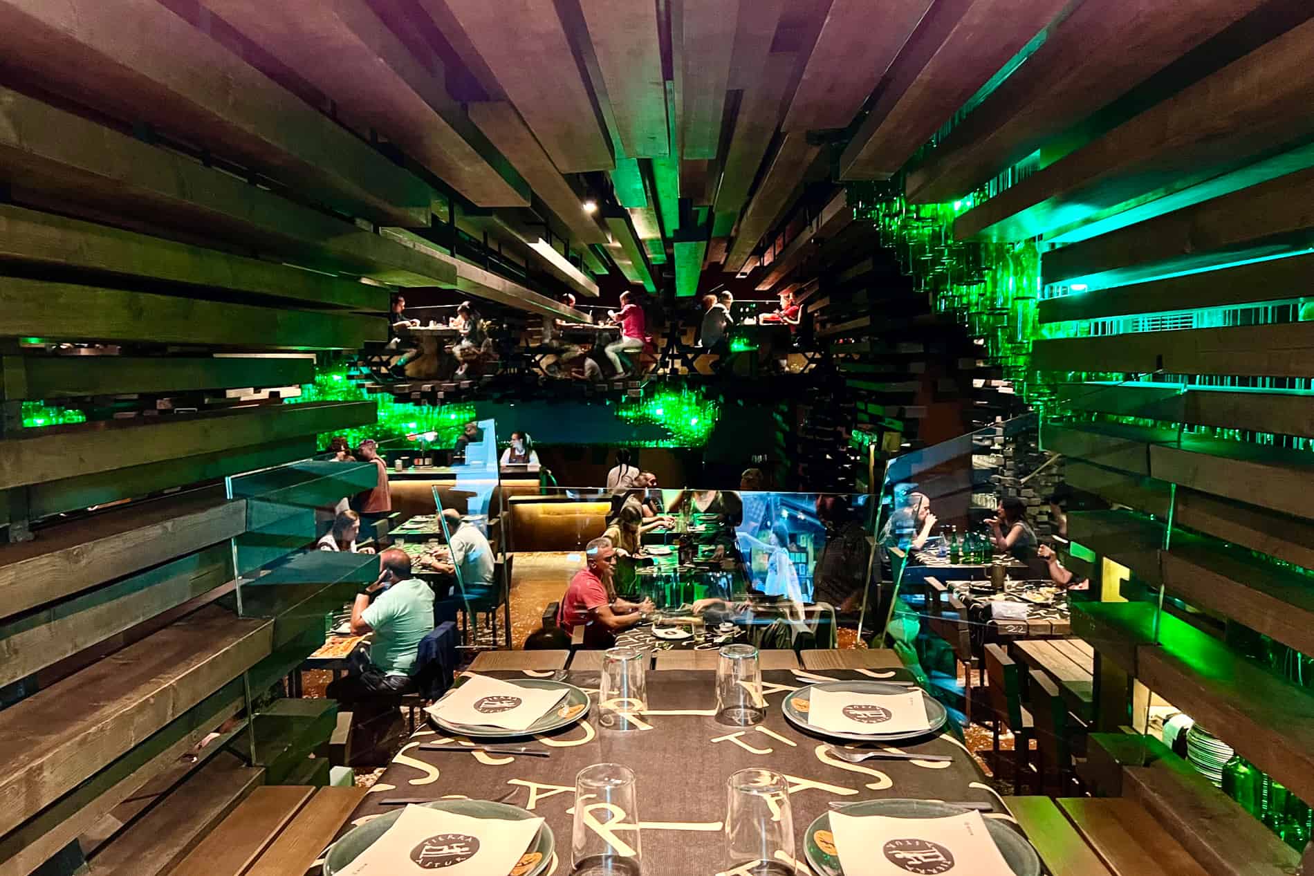 View from a table inside the Tierra Astur cider bar in Oviedo, with an interior of wooden panels and hanging green glass cider bottles. 