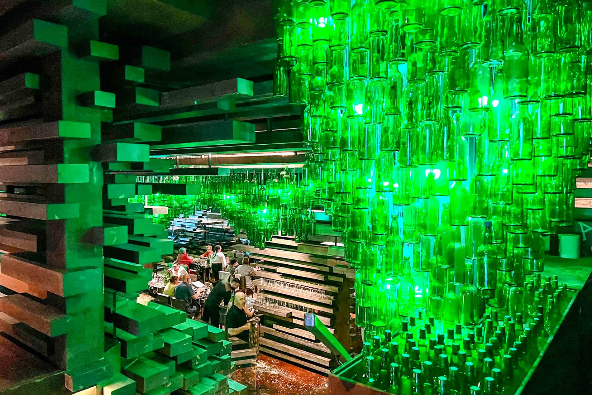 The Tierra Astur cider bar in Oviedo, with an interior of wooden panels and hundreds of hanging green glass cider bottles. 