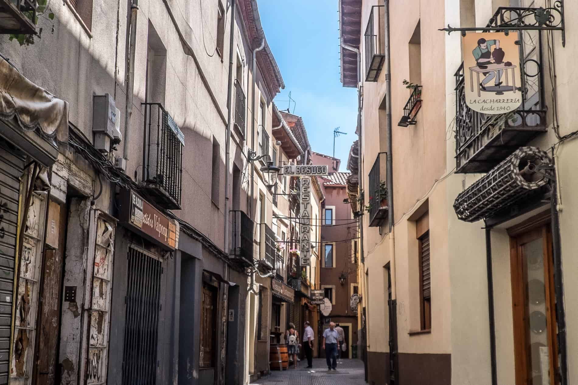 People outside on a narrow street lined with restaurants and bars in Barrio Húmedo, León.