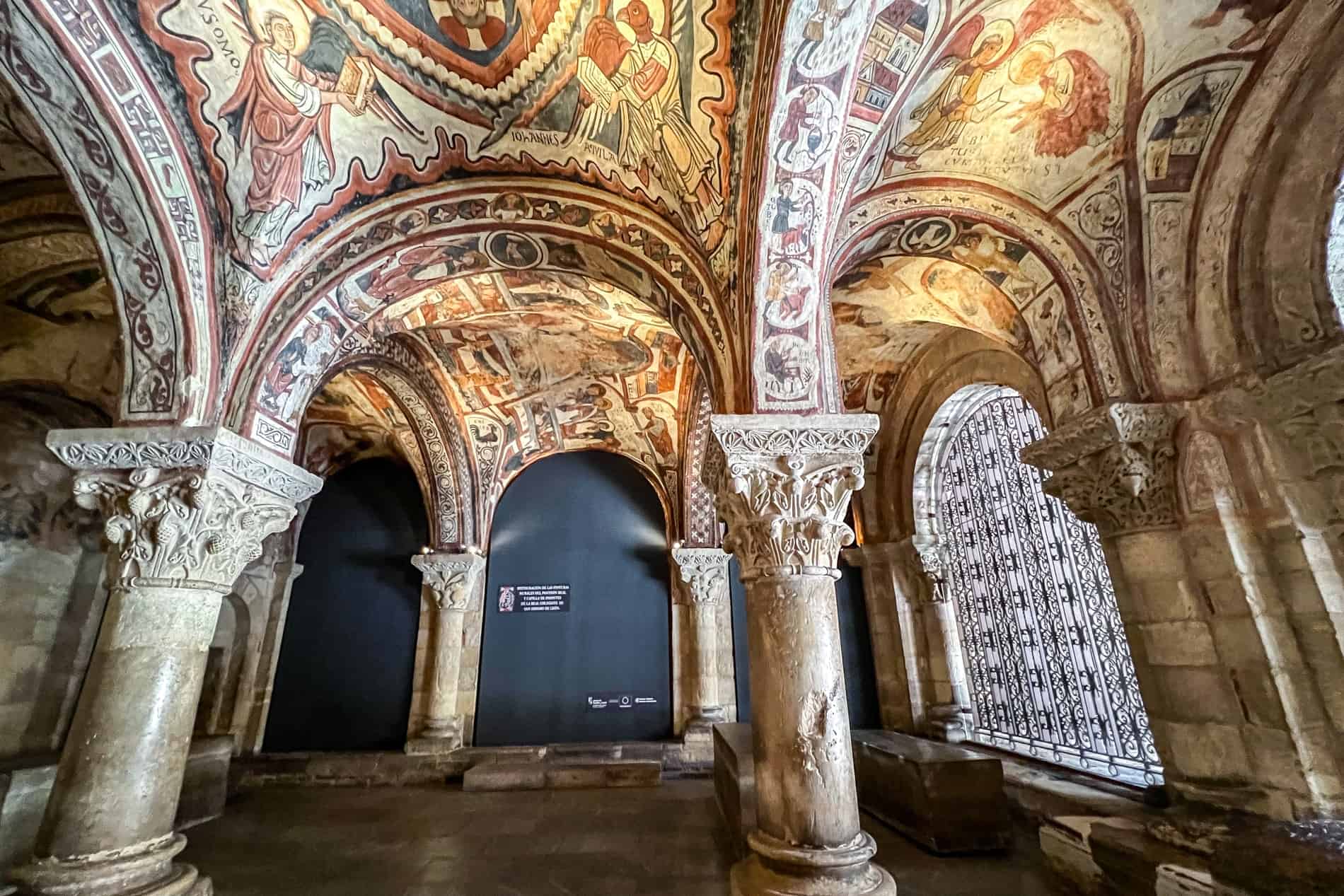 The ceiling murals above marble columns in The Royal Pantheon of the Kingdom of León.