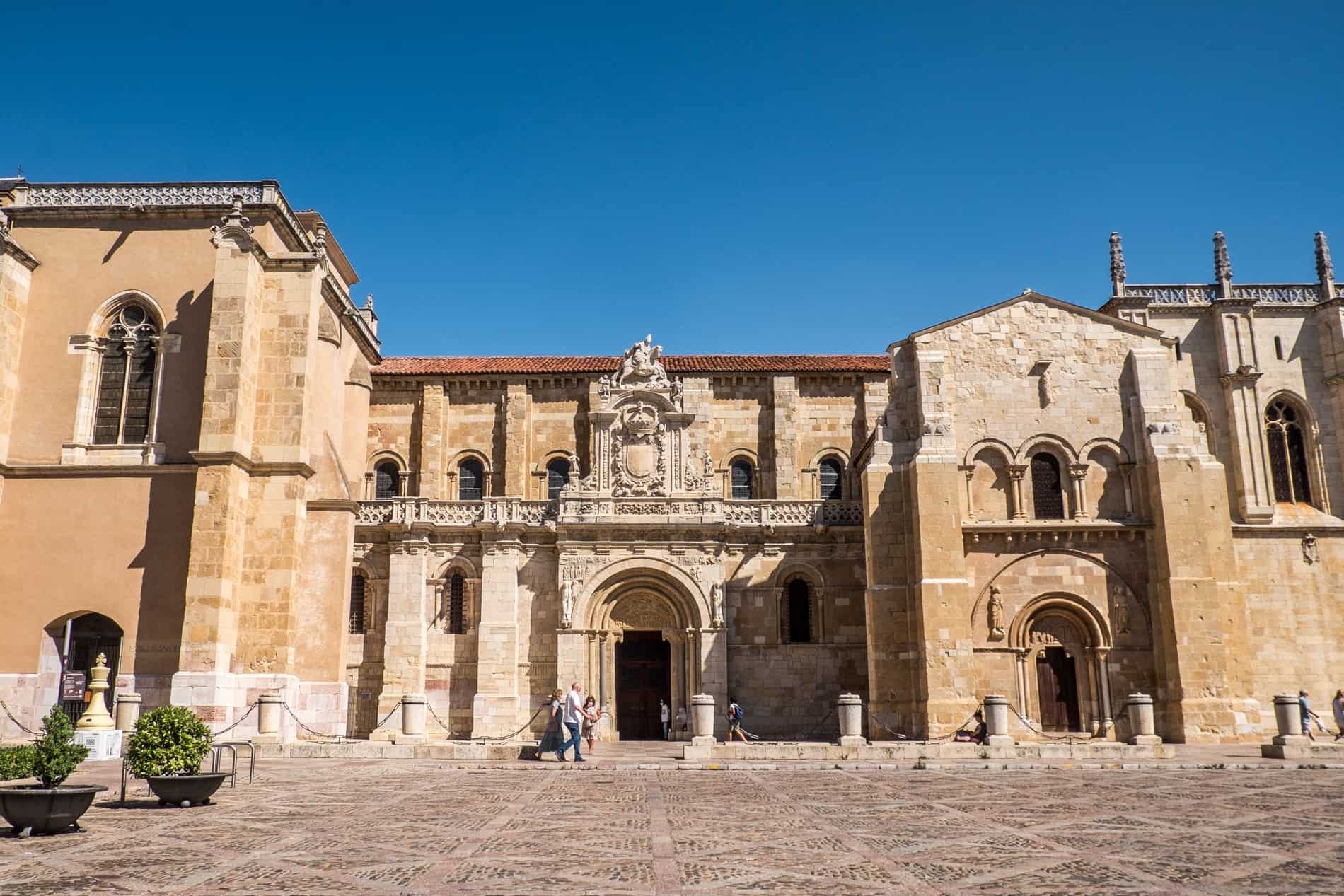 The golden Romanesque facade of the Basílica de San Isidoro de León, bright in the sun. 