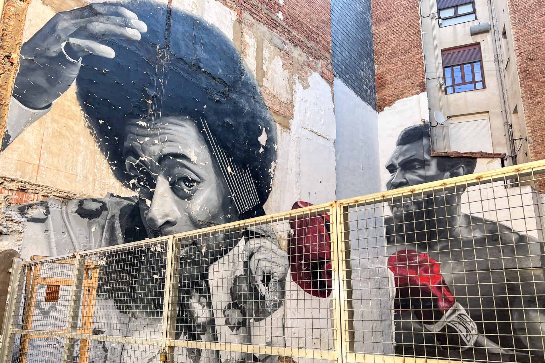 Street art of a man combing his afro and the boxer, Muhammad Al wearing red boxing gloves. 
