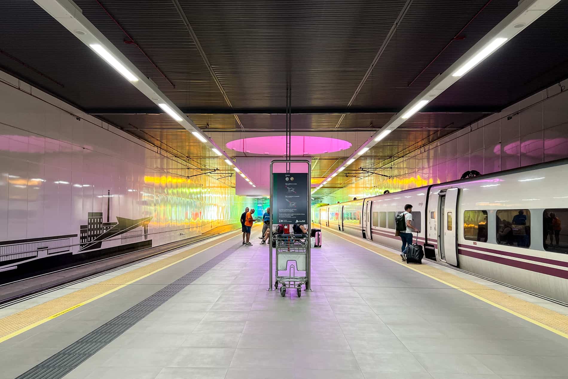 A Renfe train In Spain in León station, at a platform with a neon pink light. 