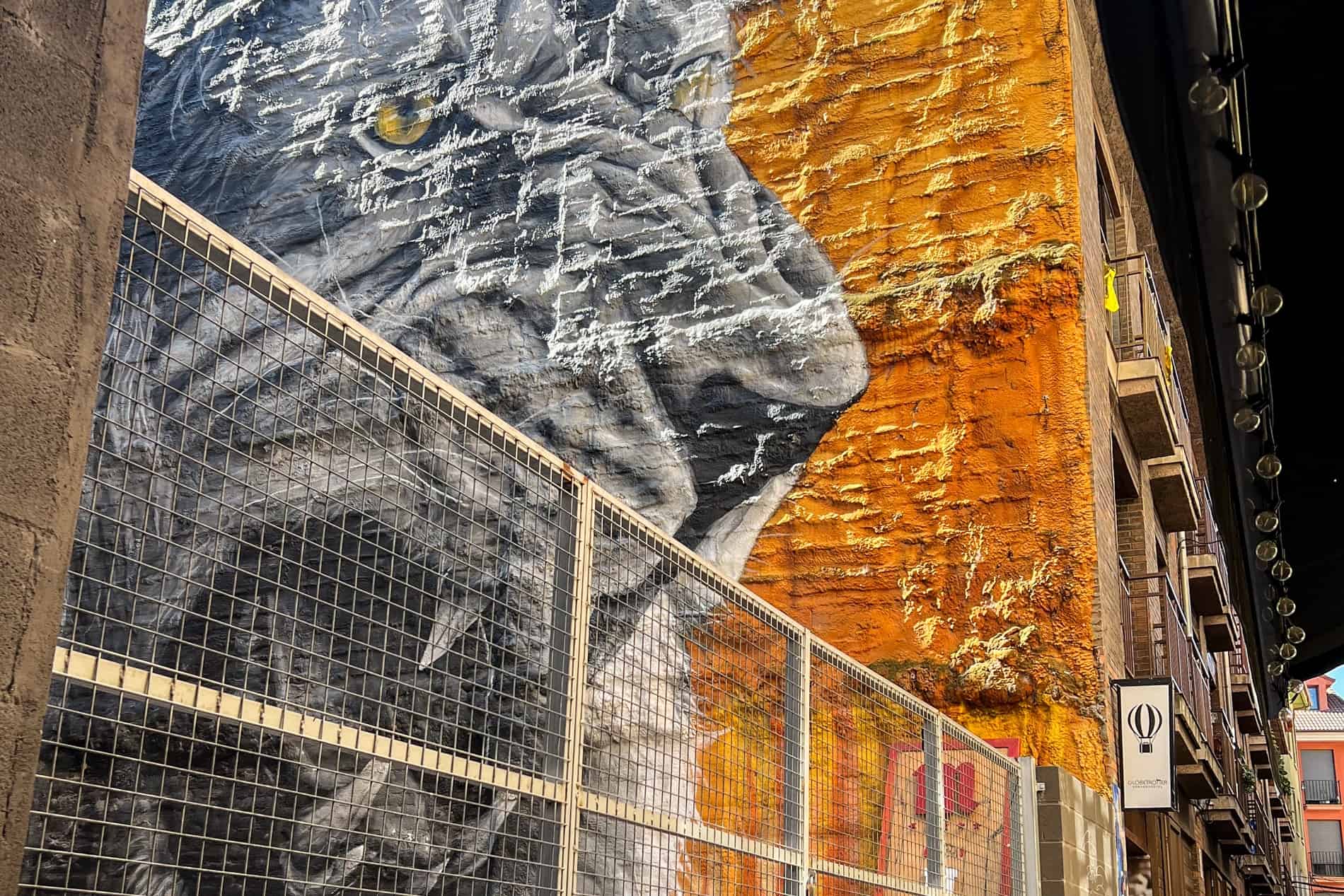 Street art of a silver-grey lion on an orange background. 