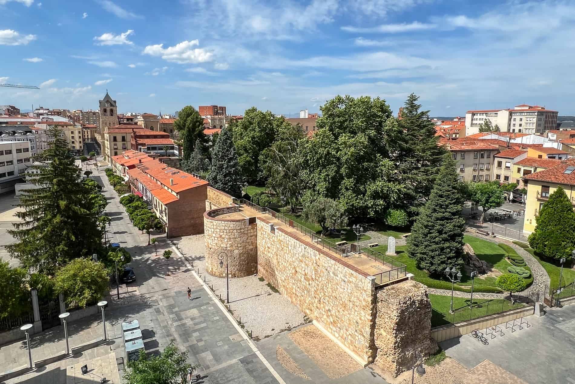 Elevated views of the Roman Walls in León, Spain between a main street and a tree-filled park. 