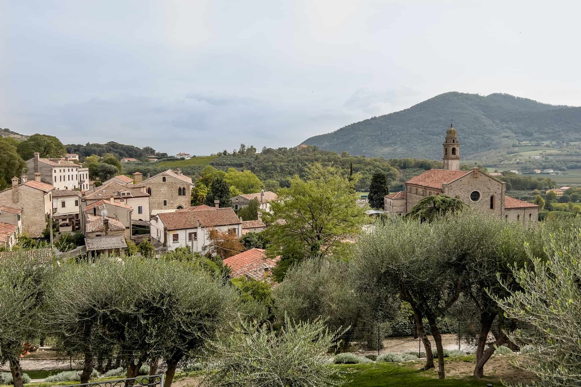 An Italian village of white-washed houses and stone dwellings within a forested valley. 