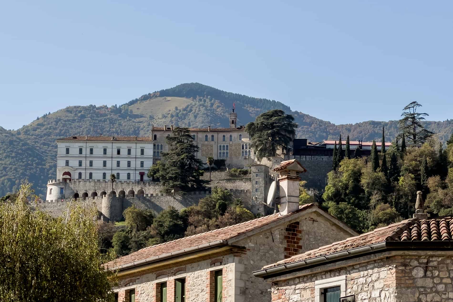 A long fortress structure on a hill overlooking Cison di Valmarino village in Veneto, Italy. 