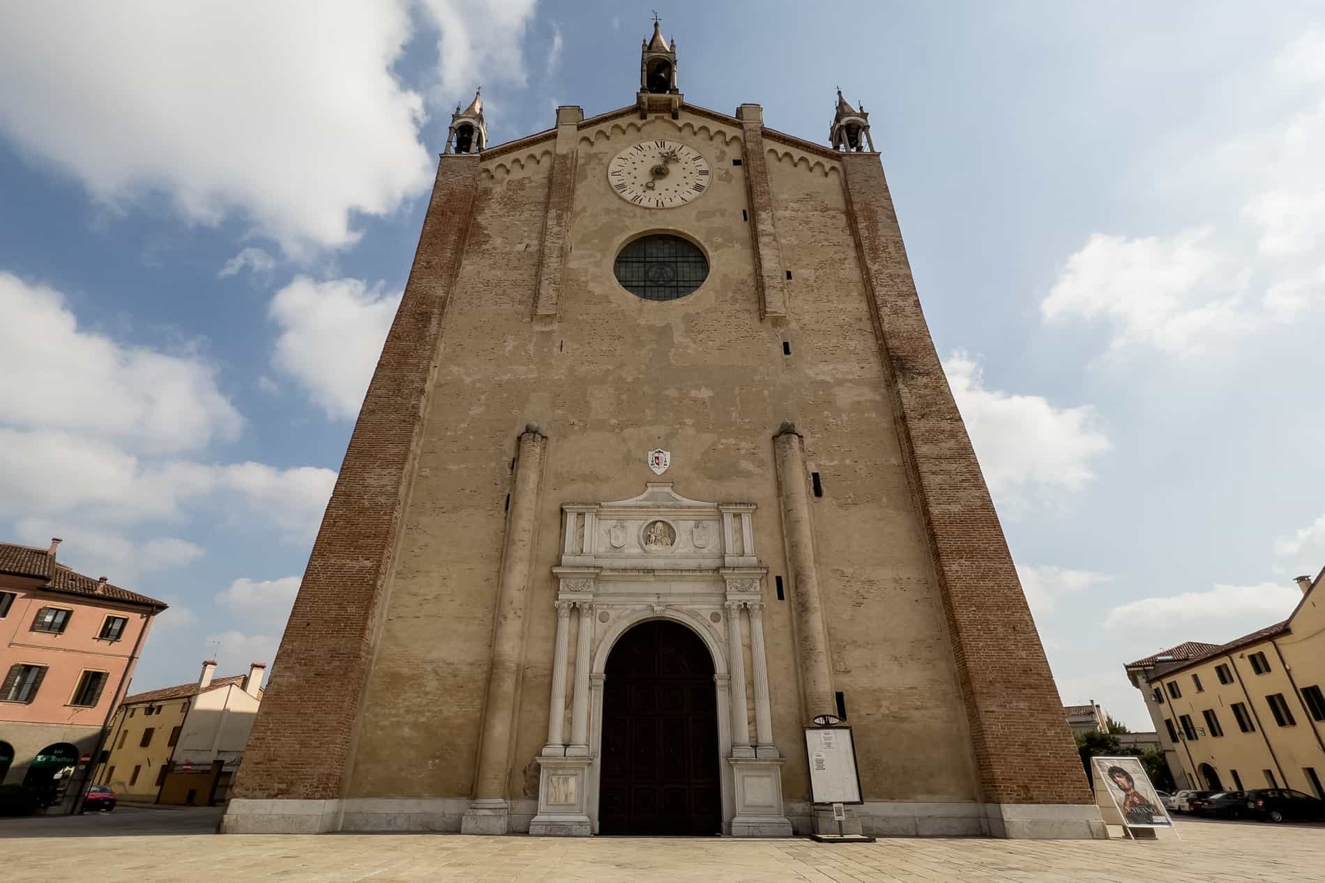 A golden stone church in Montagnana, Italy with sharp gothic and symmetrical renaissance design features. 