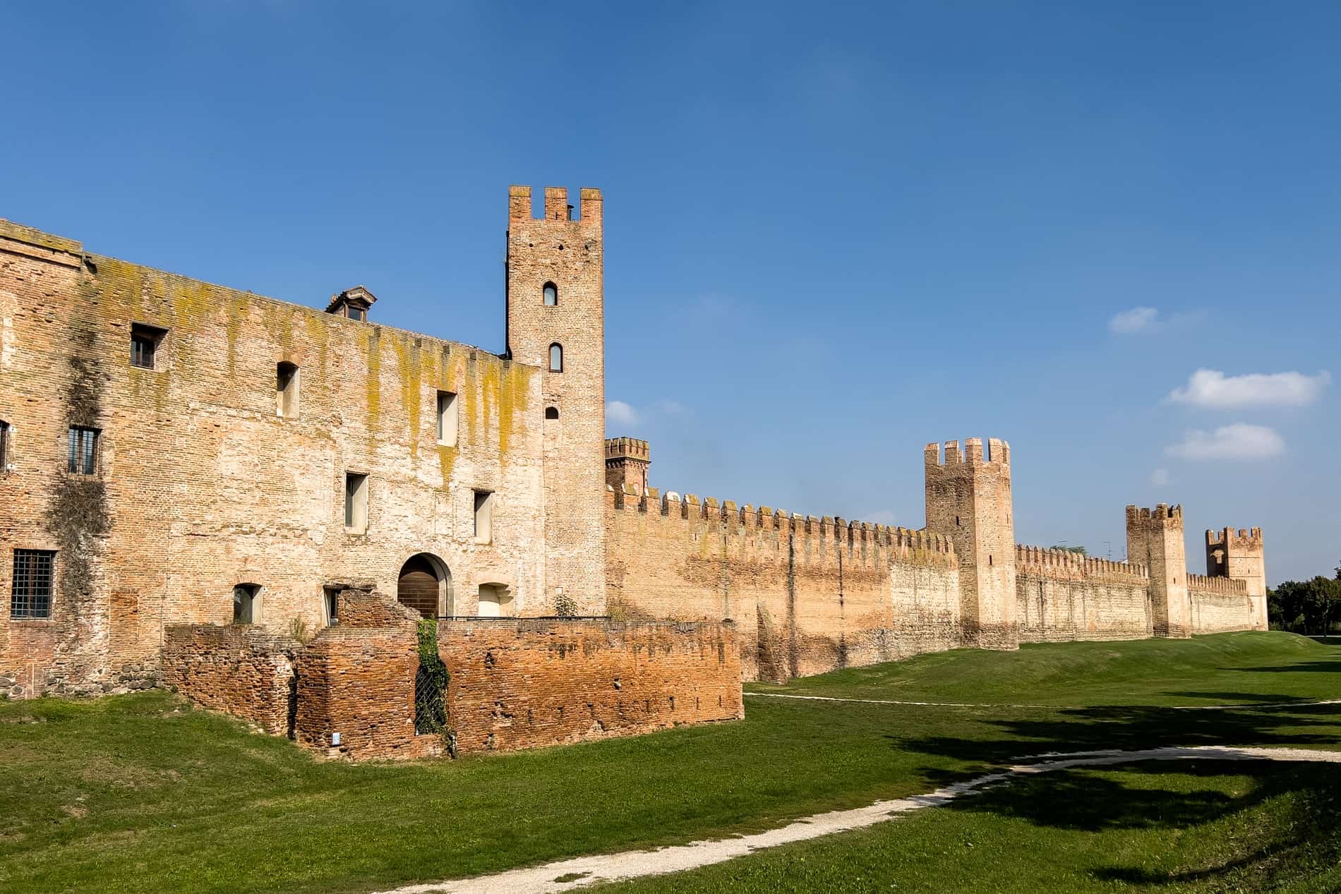 A long, golden stone fortress structure comprised of old walls and towers. 