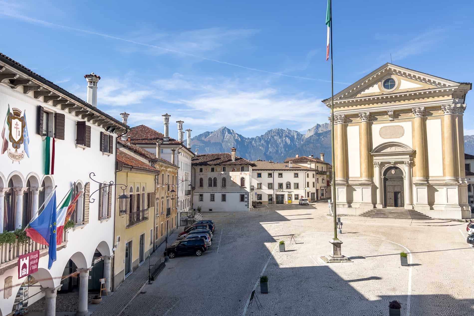 A square surrounded by Venetian villas and a classic, columned church, backed by the Dolomites mountains. 