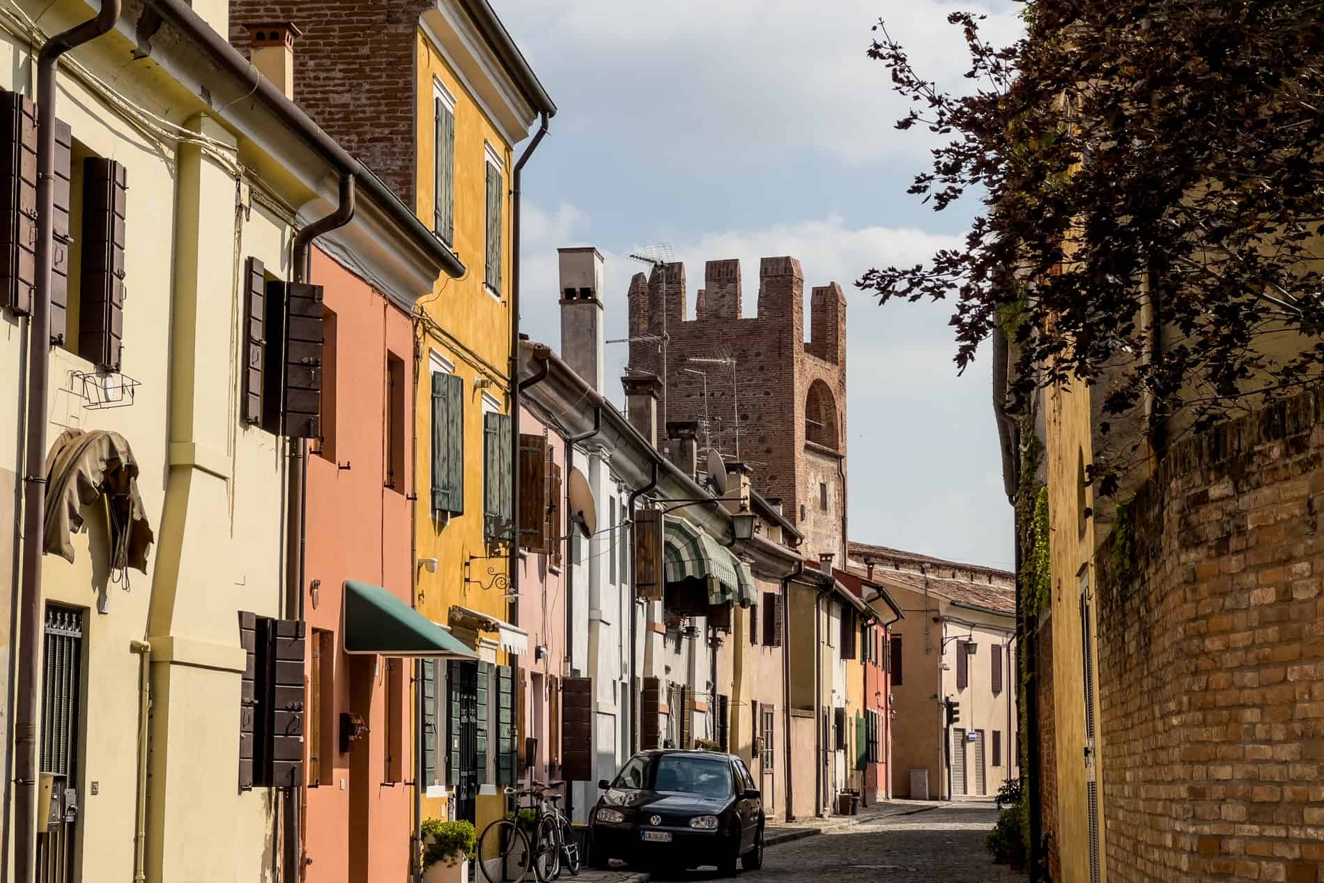 A row of colourful houses intersected by a medieval tower, in Montagnana, Italy. 