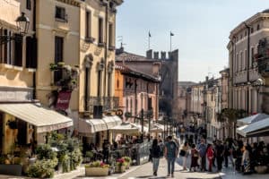 Pastel coloured buildings line a street that leads to a fortress gate in Italy's most beautiful village, Soave.