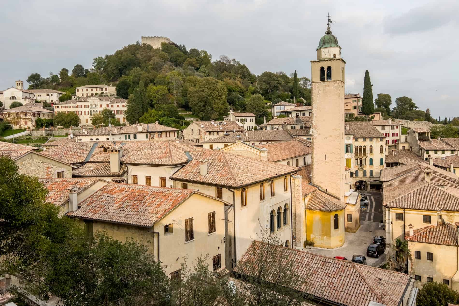 Elevated view over the brick roofed, yellow buildings in front of a hilltop fortress. 