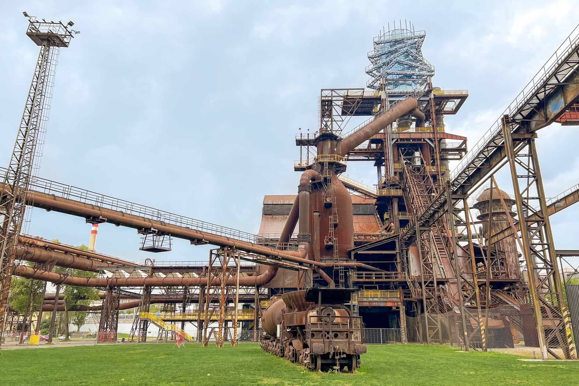 A rusty coloured industrial site in Ostrava with a glass tower structure. 