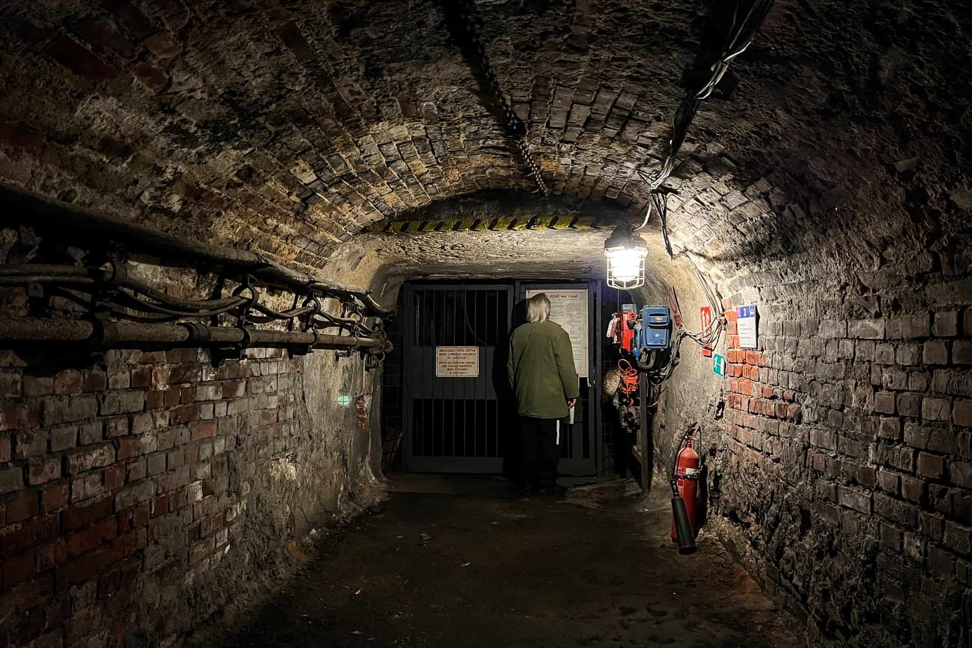 A man stands at the door of lift in a mine shaft. 