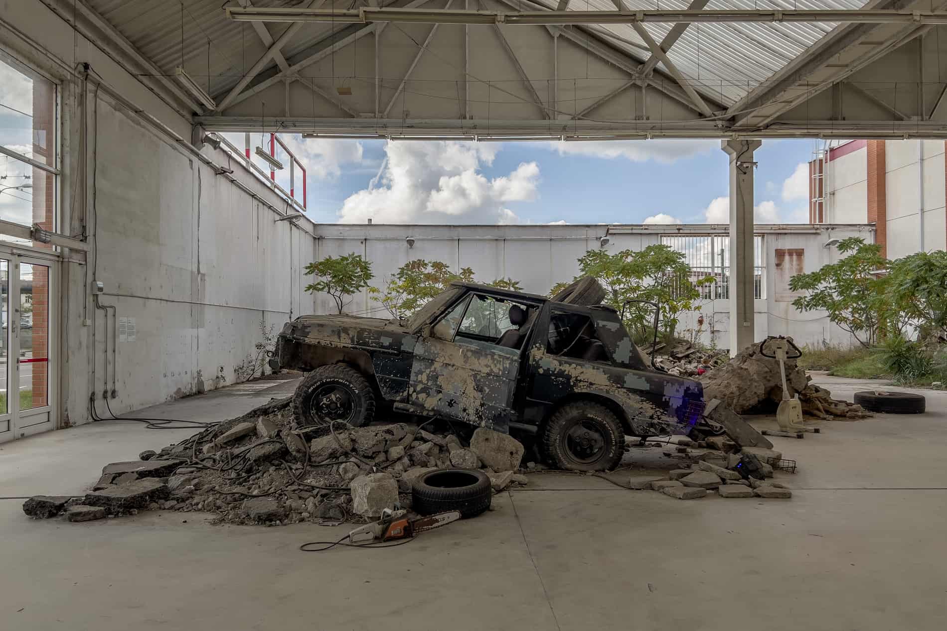 A rusting car on top of broken stones inside a contemporary art gallery in Ostrava. 