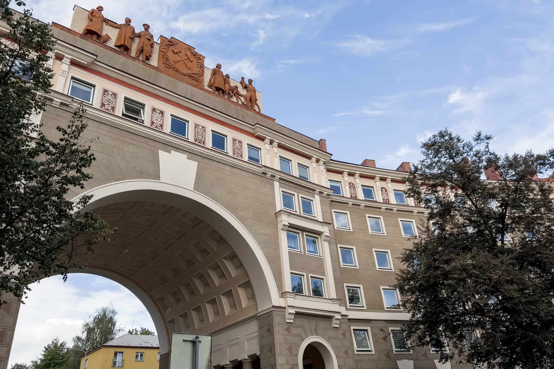 A communist style residential building in Ostrava, topped with an ochre red socialist motif with hammer and sickle. 