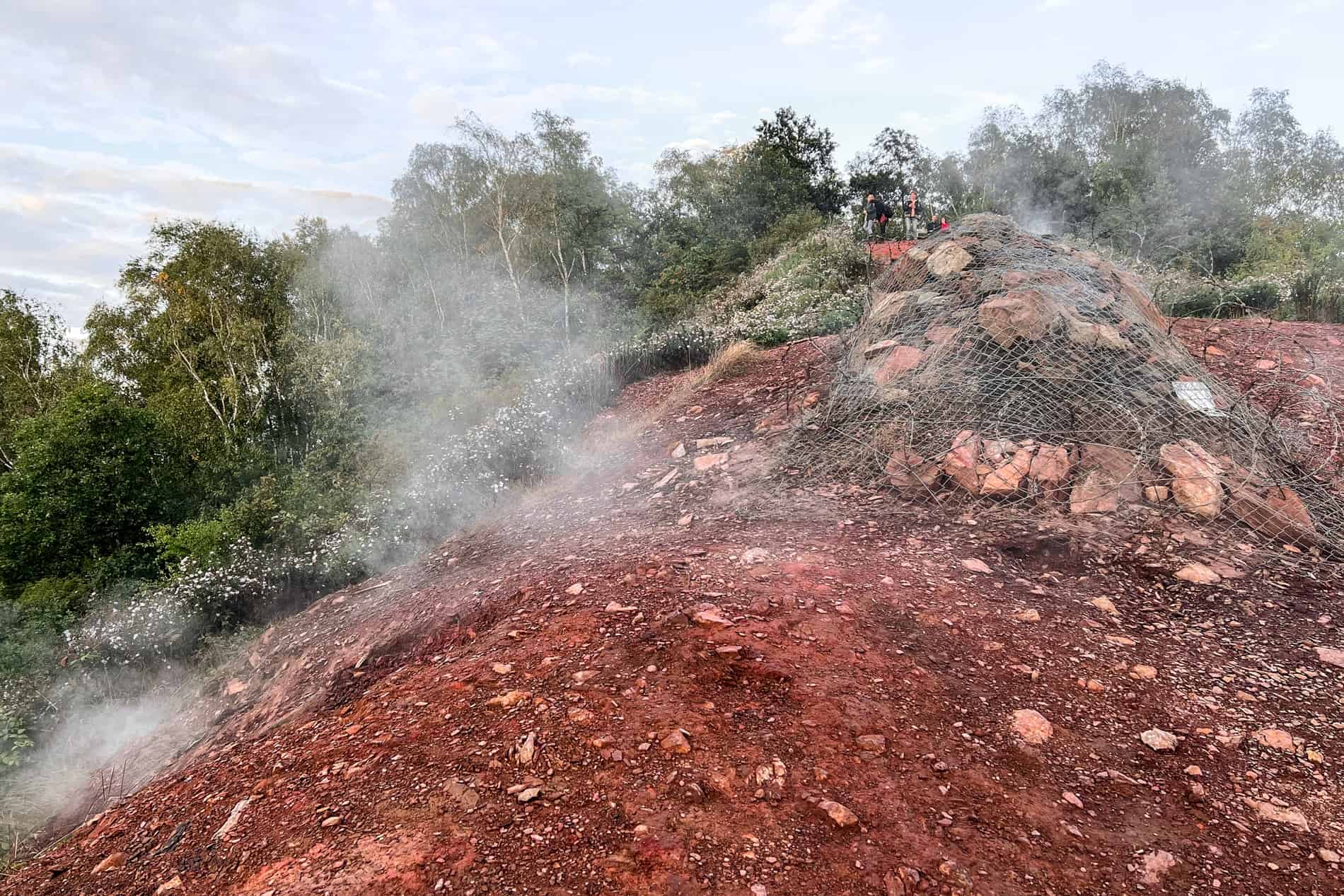 People standing at the top of a smoking hill and slag heap in Ostrava. 