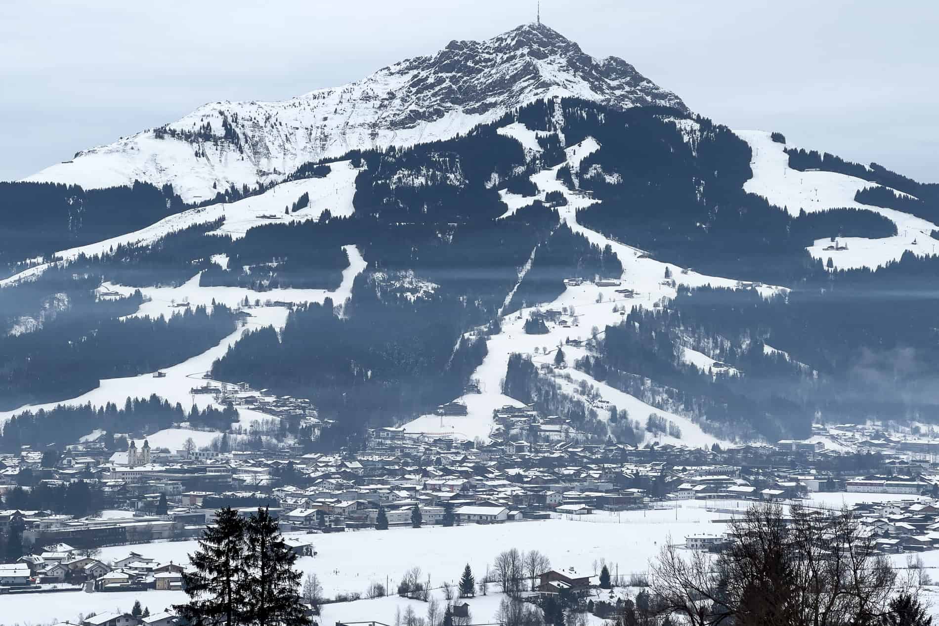 The Kitzbüheler Horn mountain in Austria covered in snow and ski slopes, rising above the village of St. Johann in Tirol. 