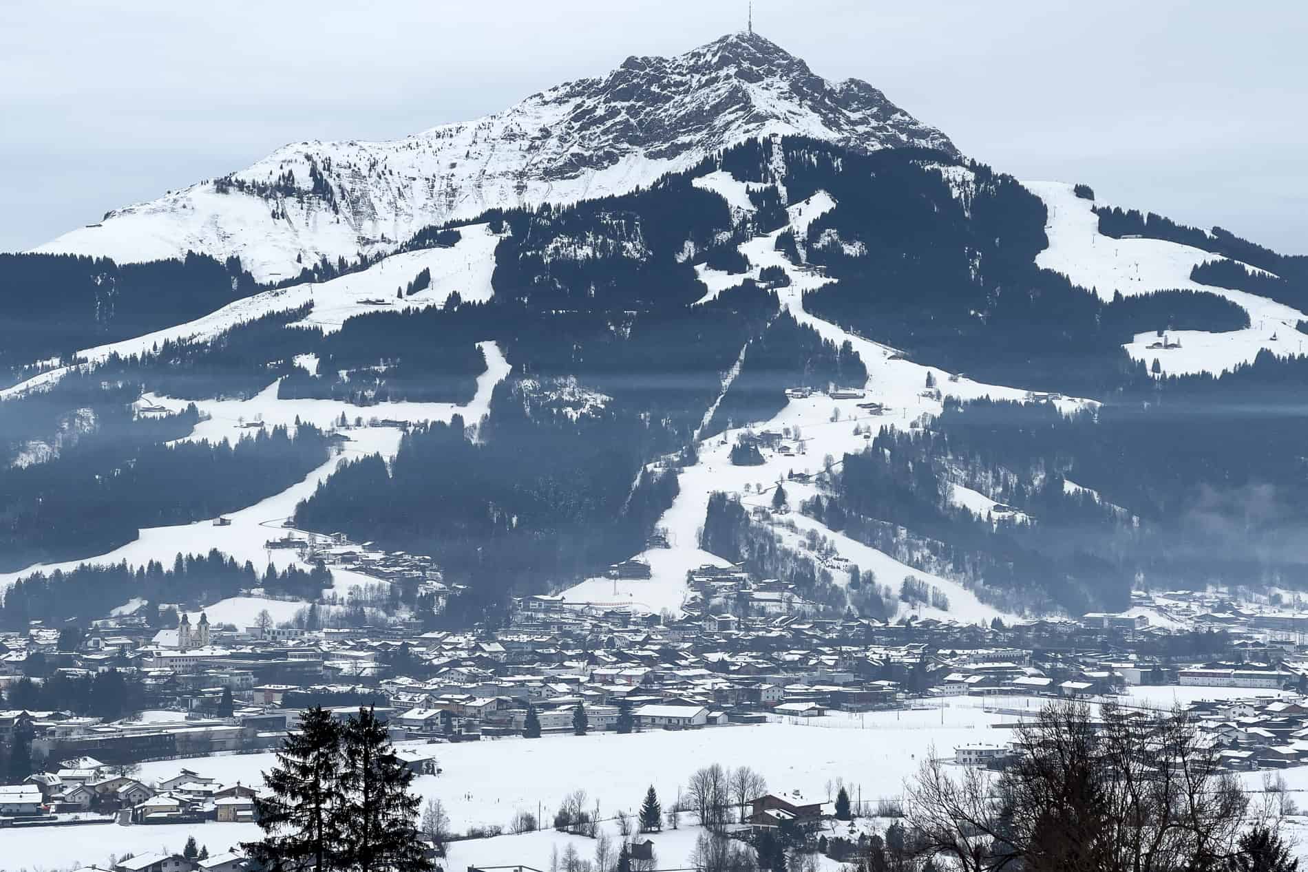 A village at the foot of a snowy ski slope mountain.