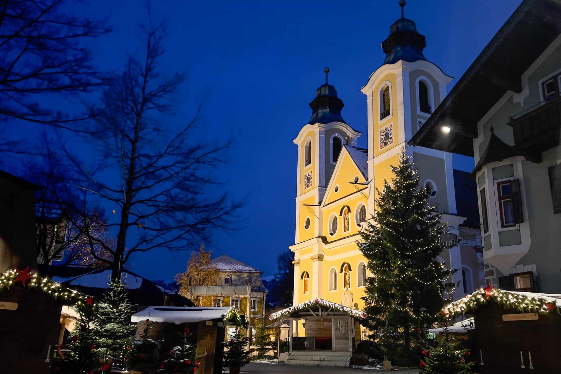 St. Johann in Tirol, Austria at night, with Christmas lights and the glowing yellow church. 