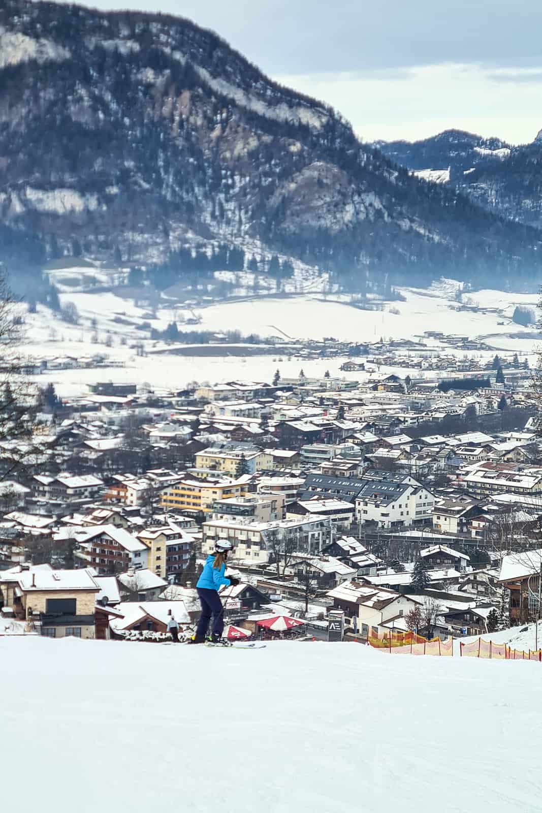 A skiier at the end of a run that looks over and leads into the town of St. Johann in Tirol. 