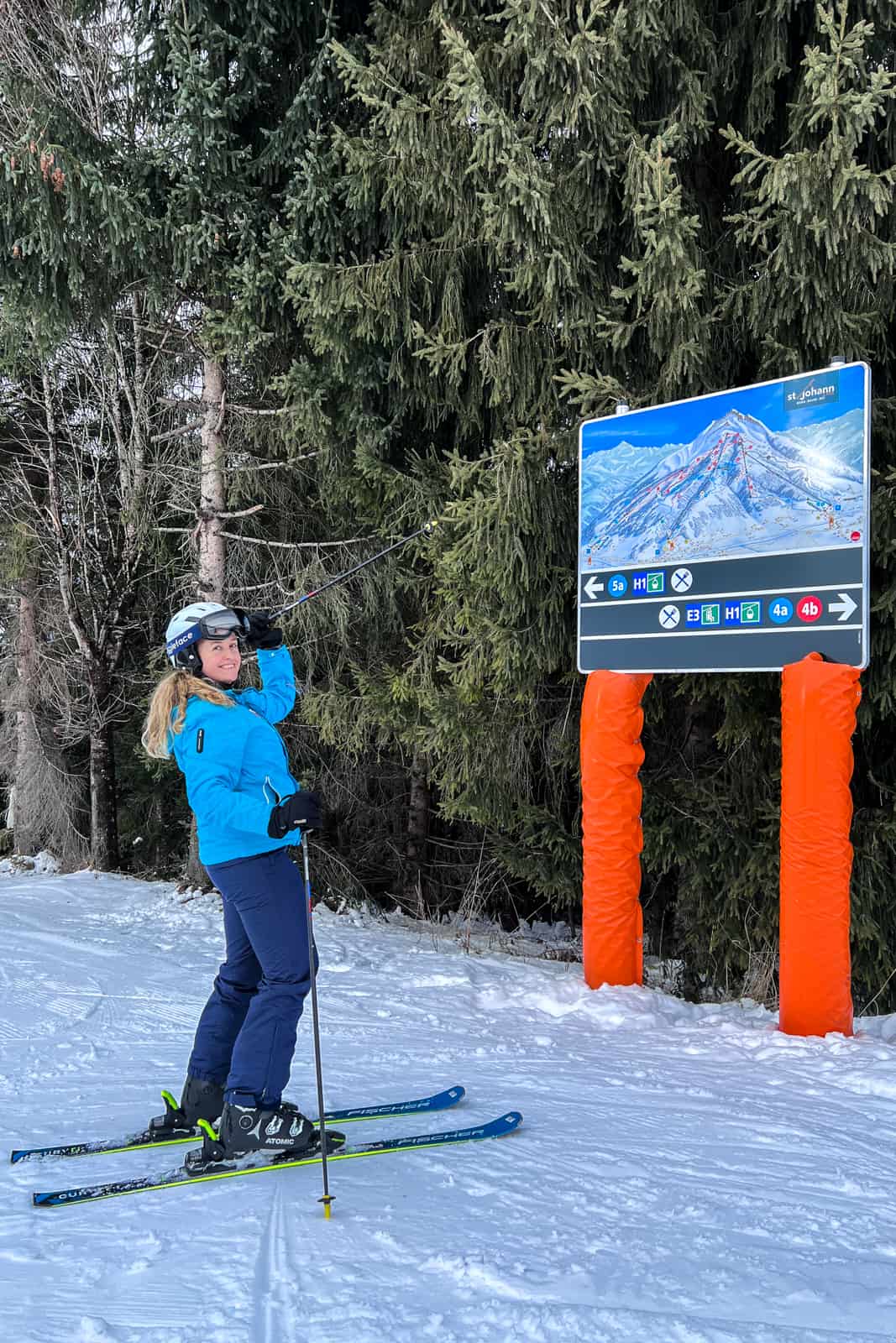 A woman on ski points with her stick at the ski map of the Kitzbüheler Horn area. 