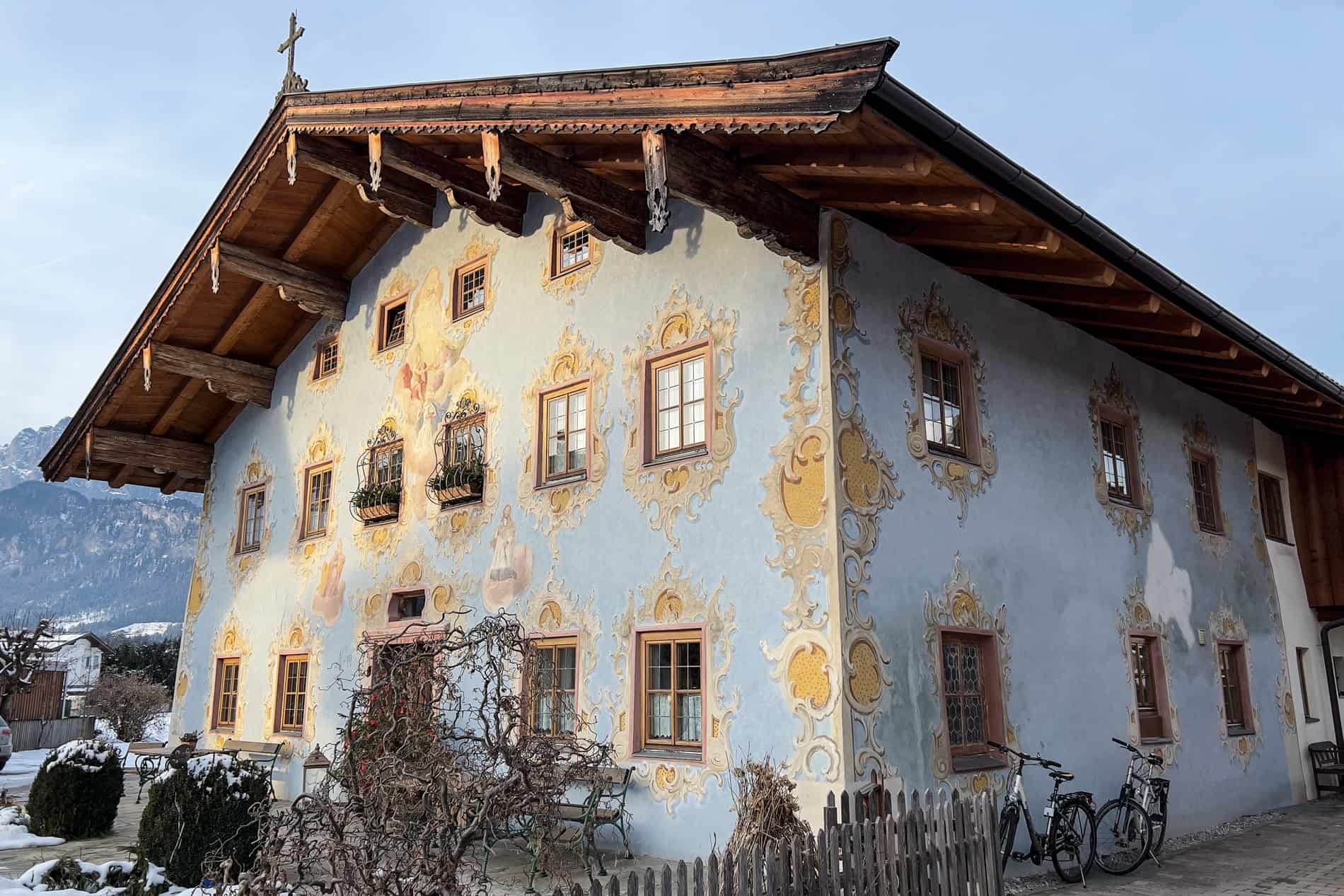 A traditional alpine house in Austria with a wooden roof and painted motif facade. 