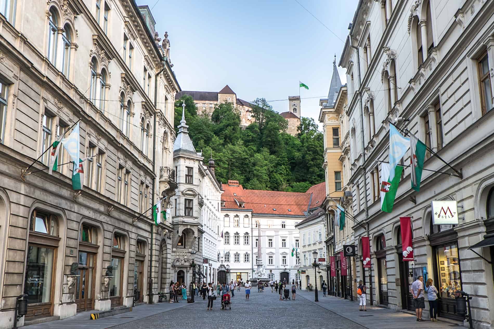 Wide street view to Ljubljana castle on the top of the forested hill.