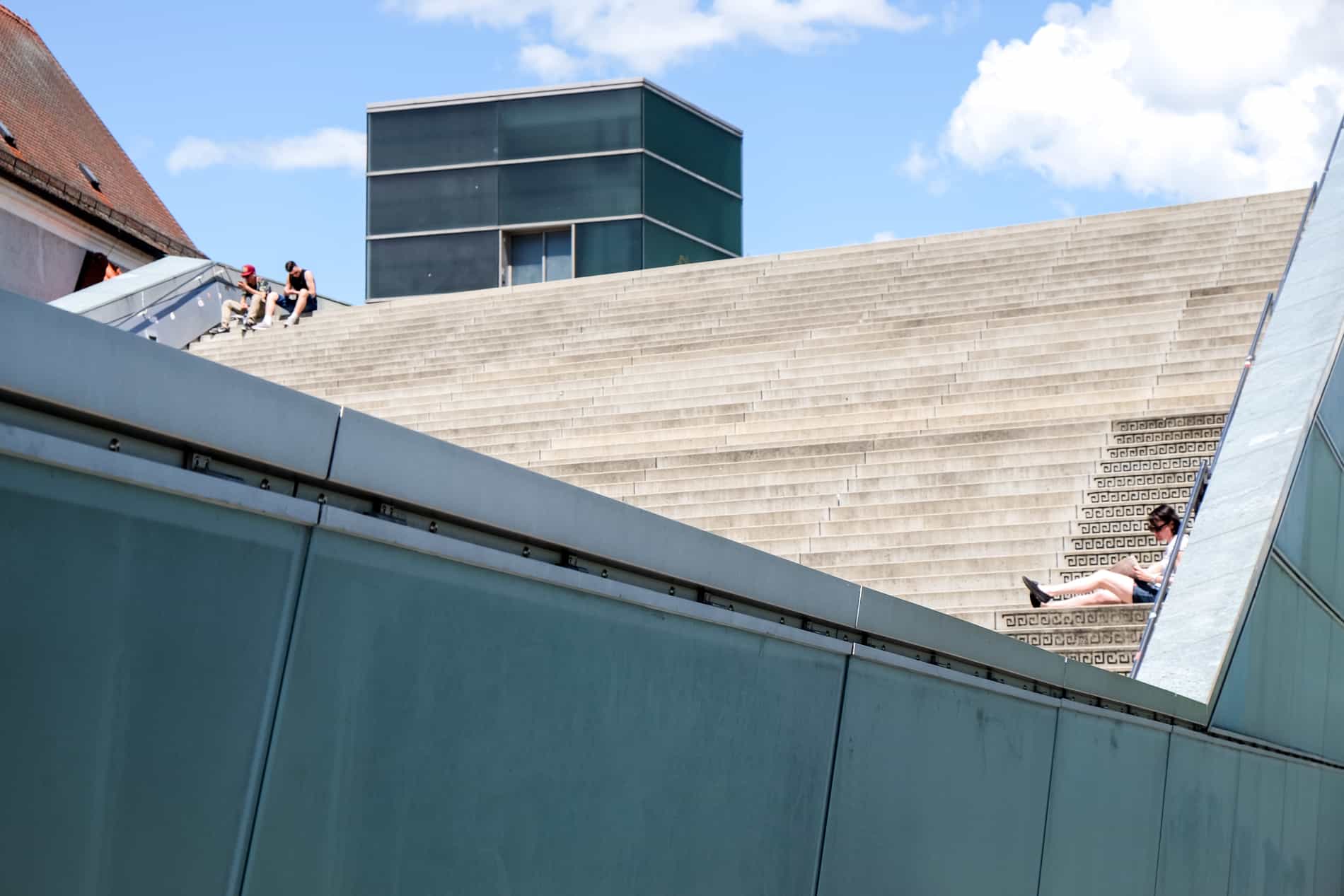 People sitting on the steps of a sloping roof of a museum in Linz city, Austria. 