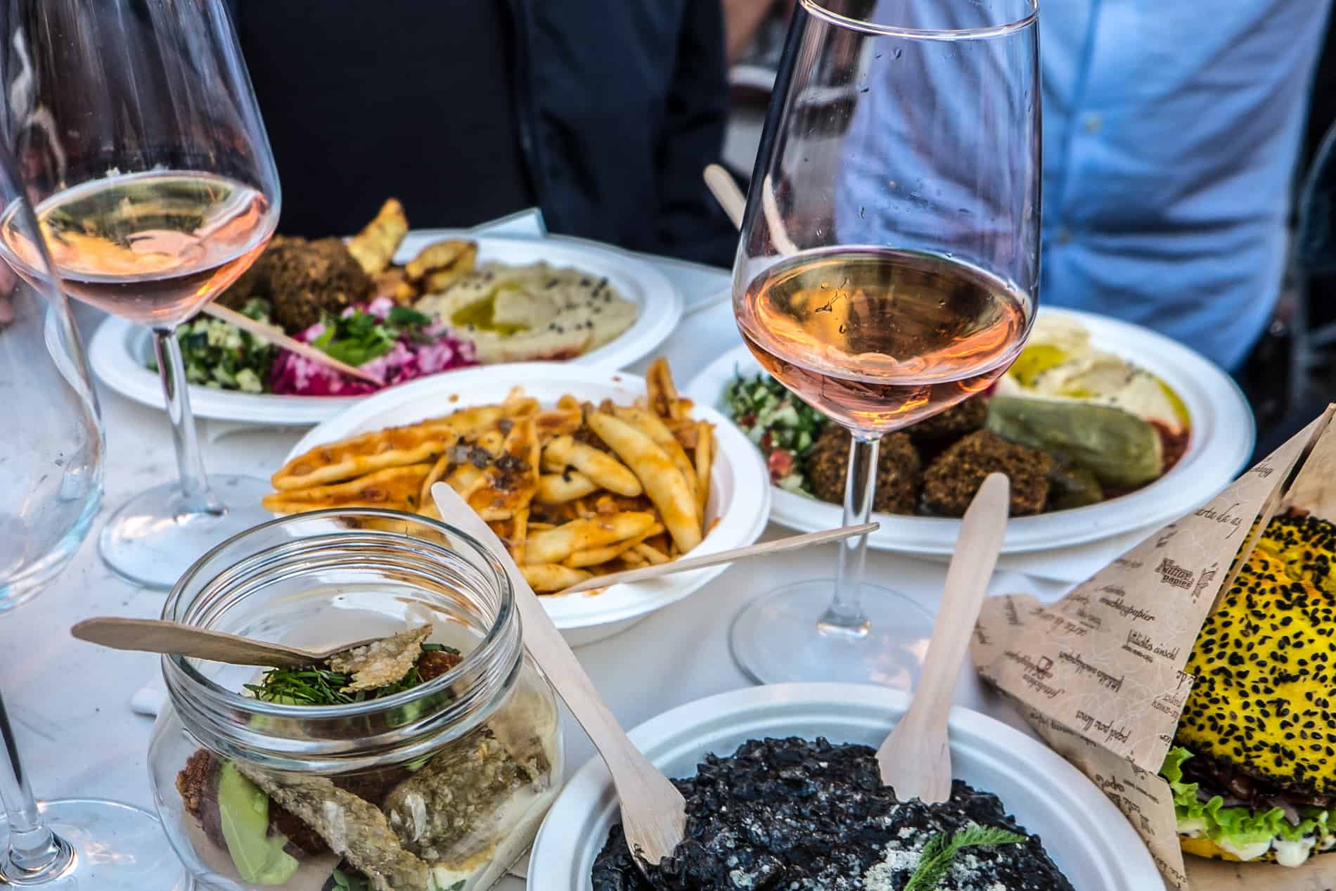 A selection of food dishes and glasses of wine on a table at at Ljubljana's outdoor Open Kitchen Market. 