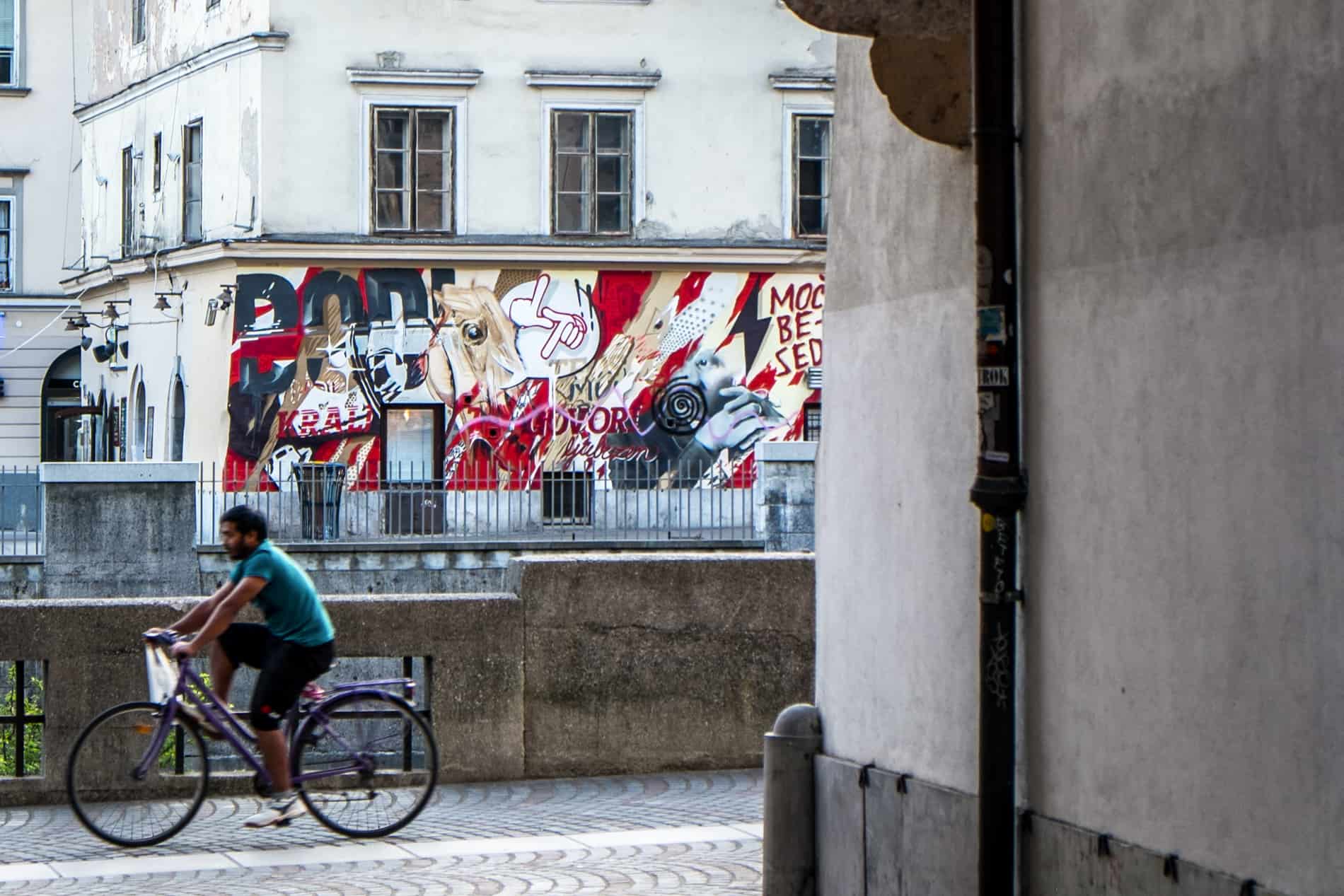 A cyclist passing a small street art mural in Ljubljana old town. 