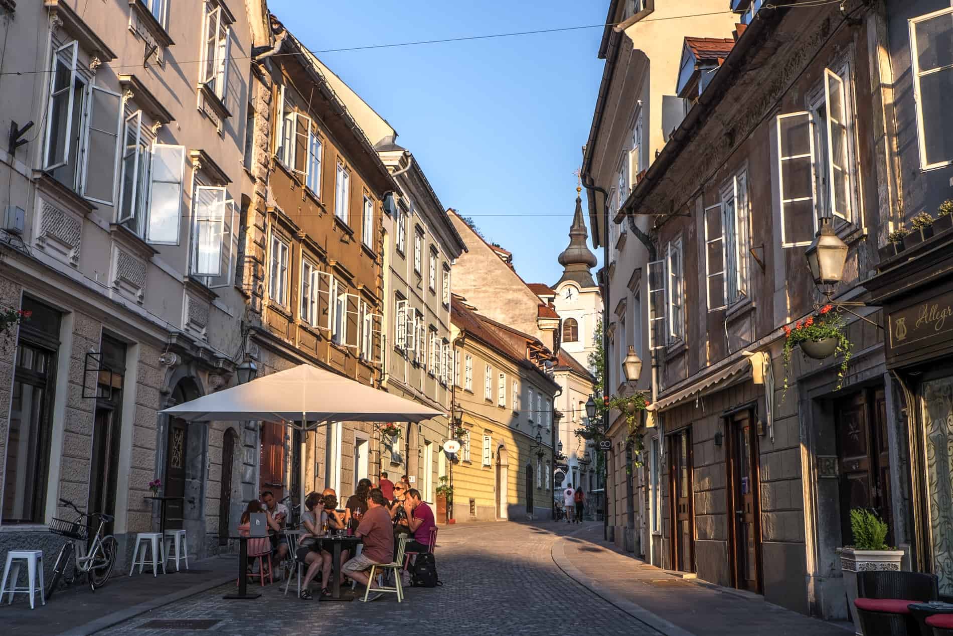 People al fresco dining at golden hour in a pretty street in old town Ljubljana. 