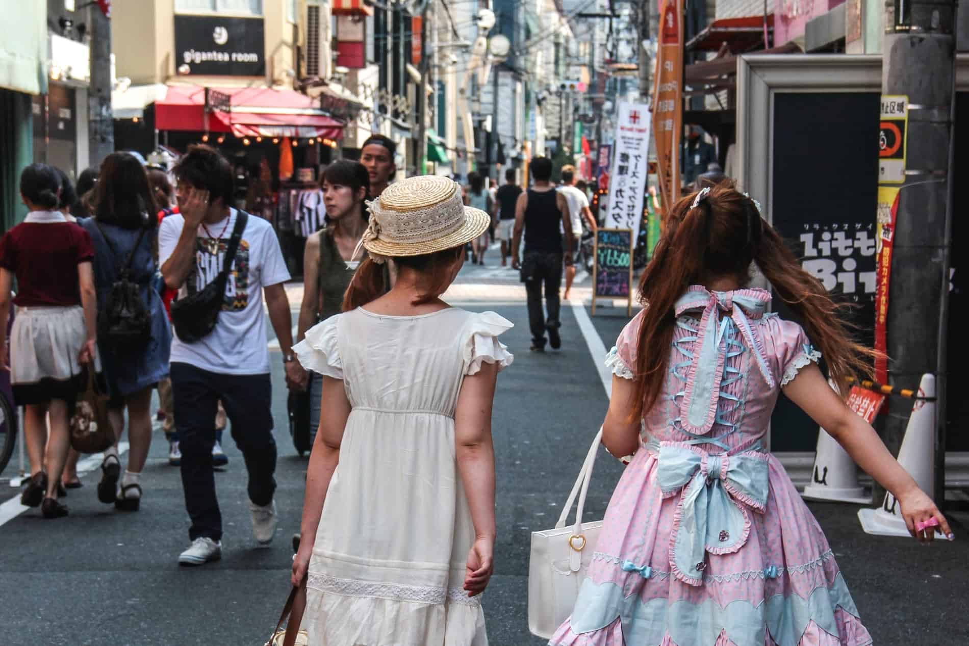 Two Japanese women in fashionable clothing on a long pedestrian street in Osaka city. 